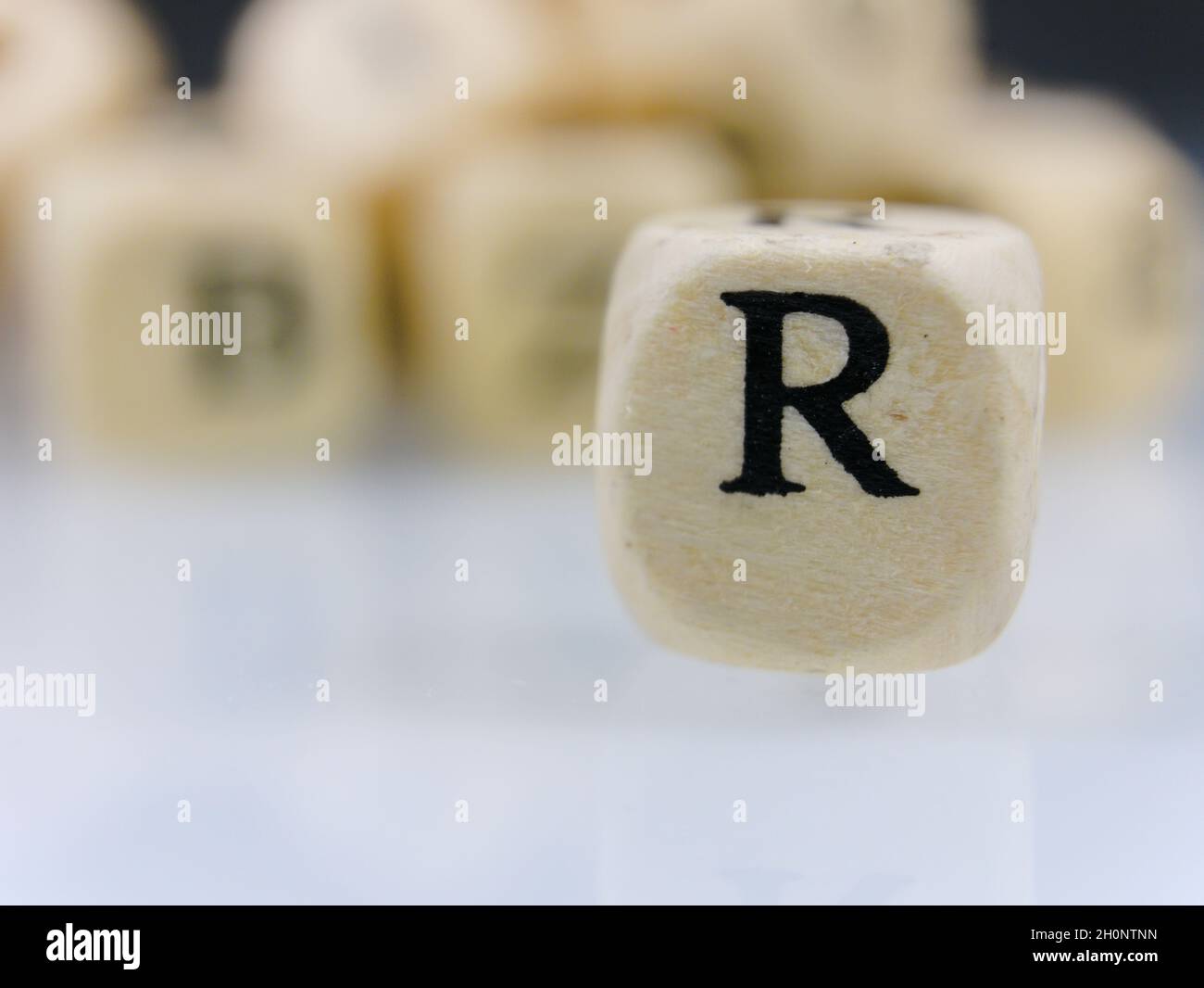 Selective focus a small wooden dice with an uppercase alphabet letter R ...