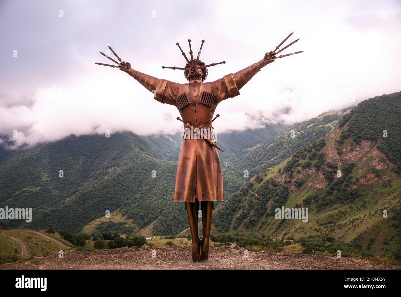 VERKHNIY ZGID, RUSSIA - 07 25 2021: Newly built Dance With Daggers monument towering along with high mountain peaks in Verkhny Zgid village. Monument Stock Photo