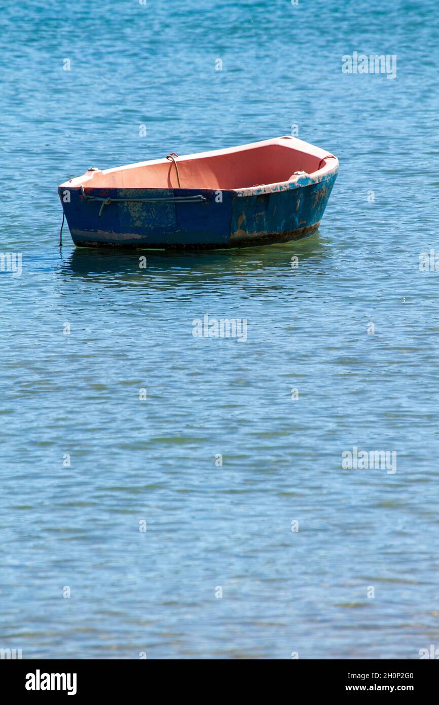 Blue hulled row boat dinghy anchored. Stock Photo