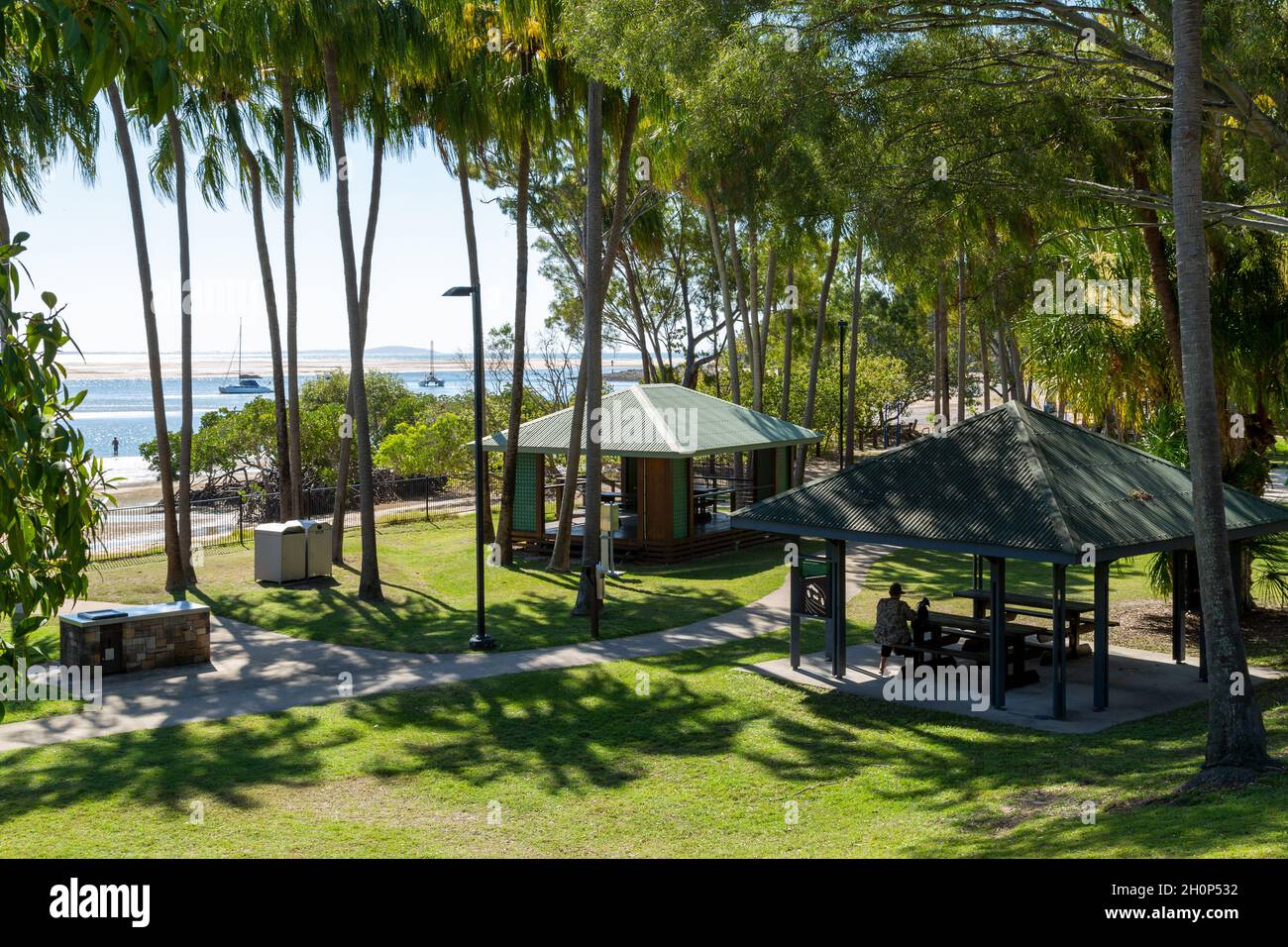Picnic shelters under palm trees, next to an estuary. Stock Photo