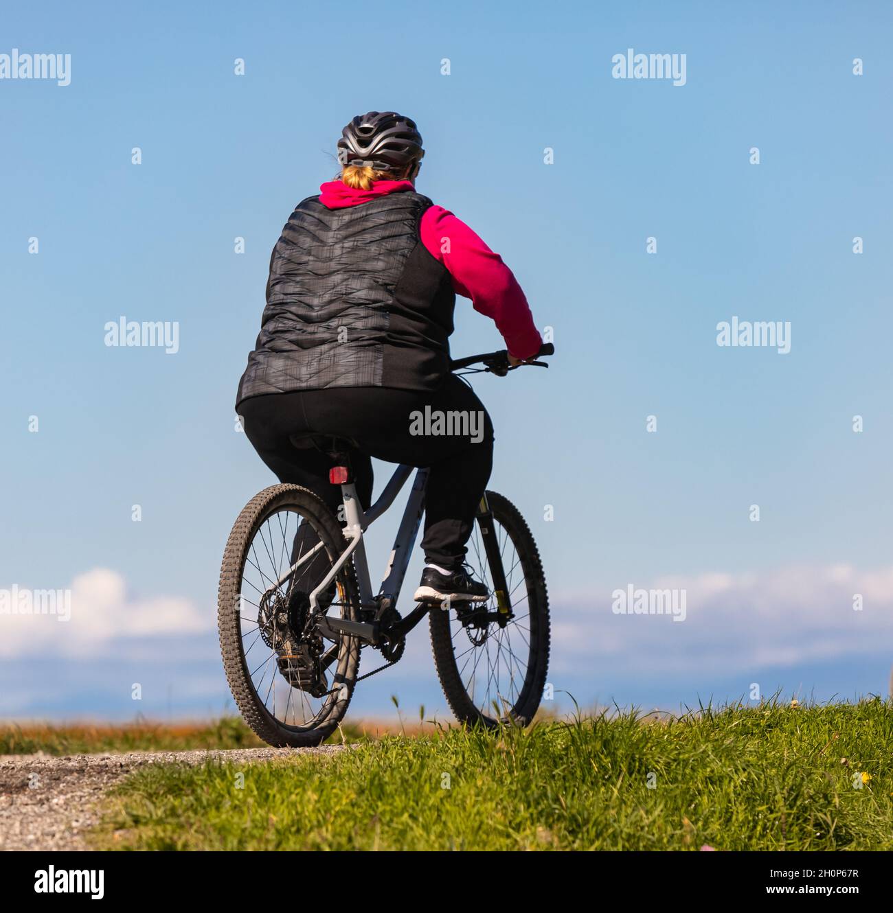 Overweight woman slimming on bicycle outdoor in the park. Healthy lifestyle concept. Street photo, selective focus, travel photo. Stock Photo