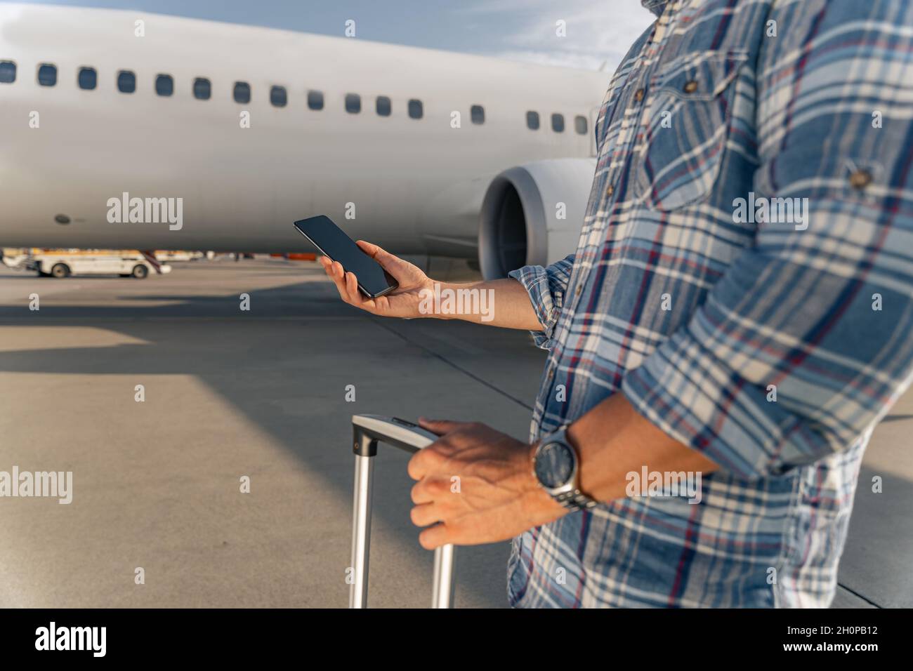 Male passenger holding a smartphone and a comb before the flight Stock Photo