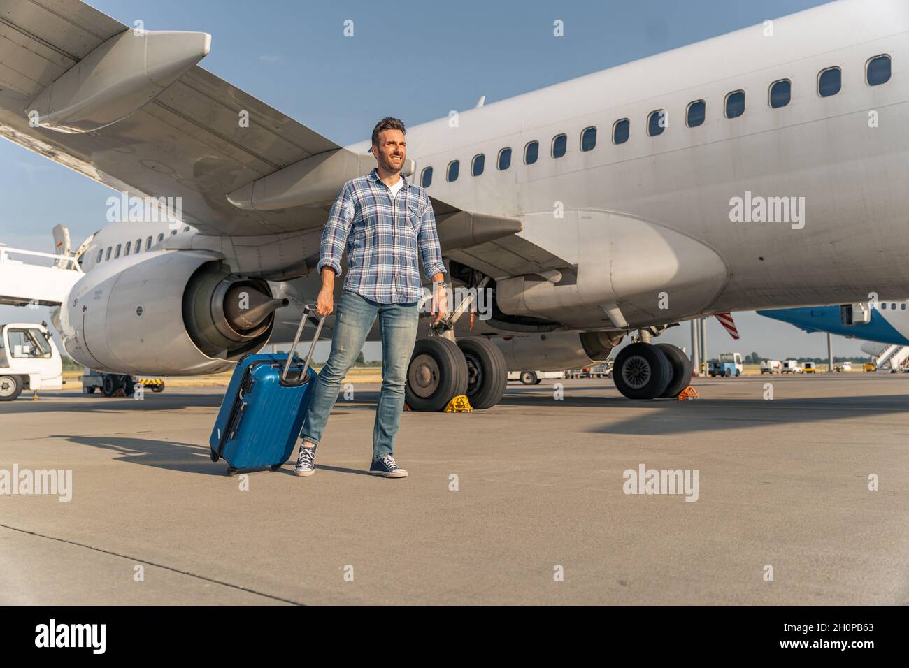 Traveler Caucasian man get off the plane with suitcase in the airport Stock Photo