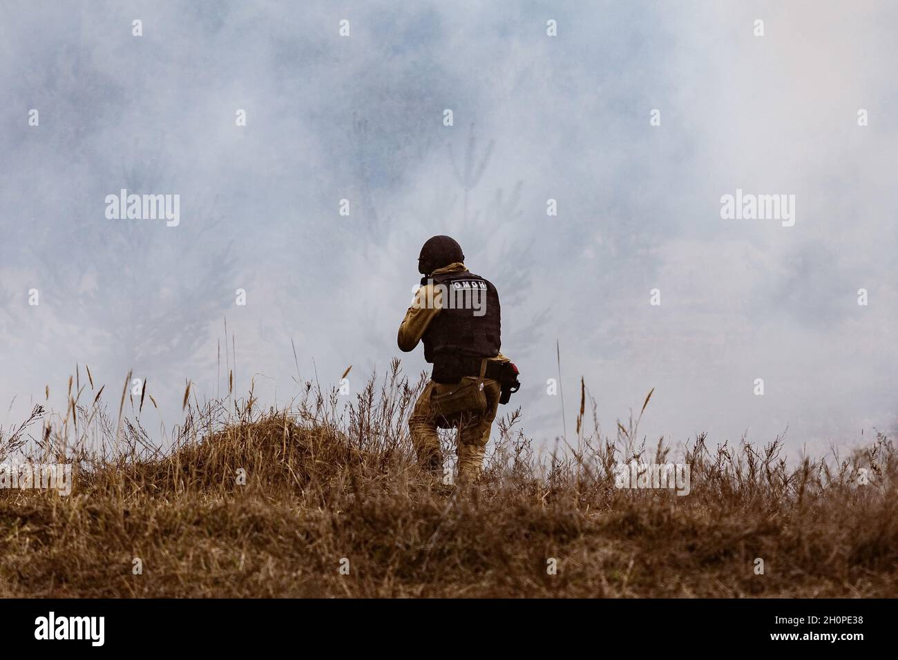 A riot policeman enters the smoke from an exploded mine, during the field phase of the exercise. A complex tactical and special exercise took place in the Voronezh region. It was attended by employees and servicemen of the National Guard and regional offices of the state power departments. Stock Photo