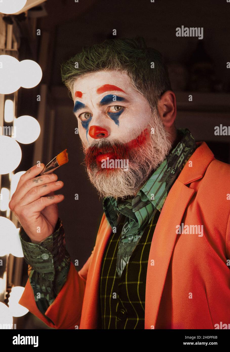Male portrait of the man who puts on makeup imitating the Joker For the Hallowen holidays Stock Photo