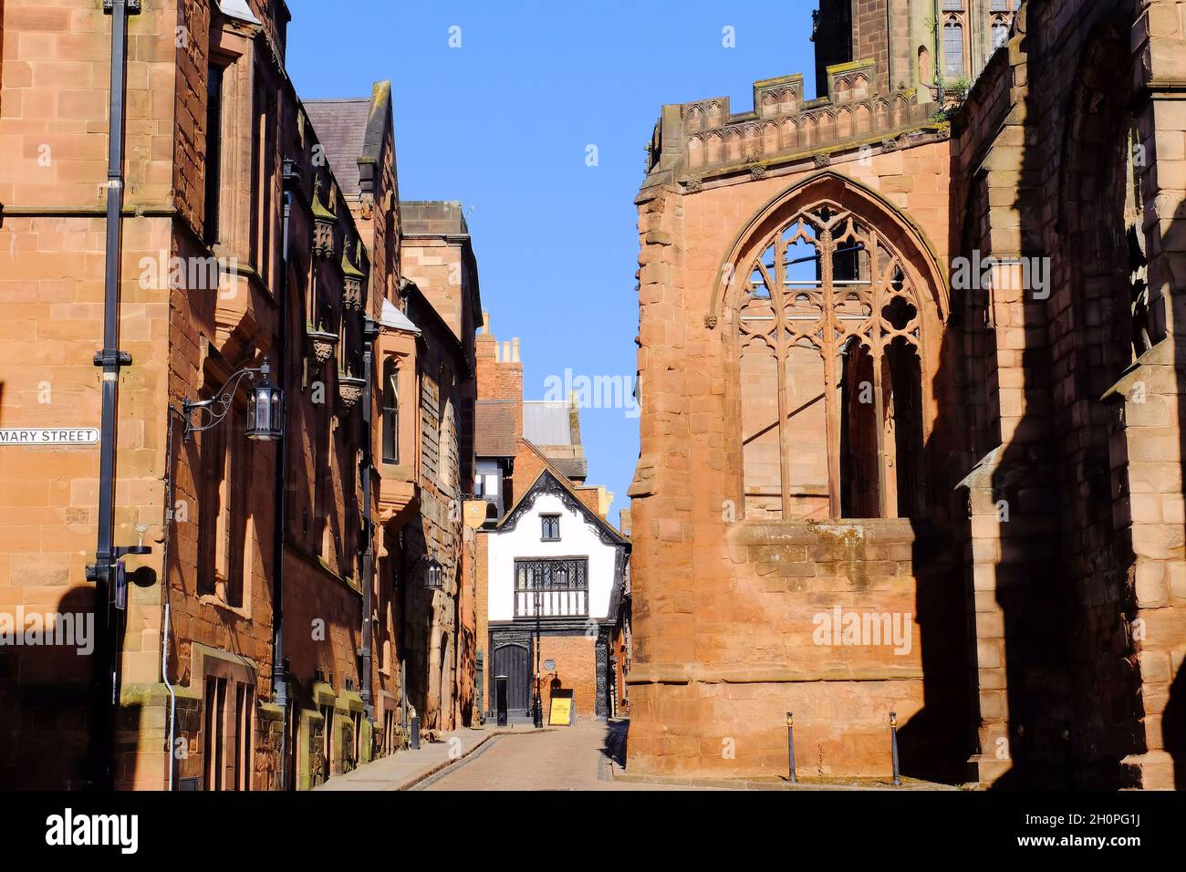 Looking down Bayley Lane from St Mary Street soon after sunrise with ruins of Coventry Cathedral and stone and half timbered buildings in Coventry Stock Photo