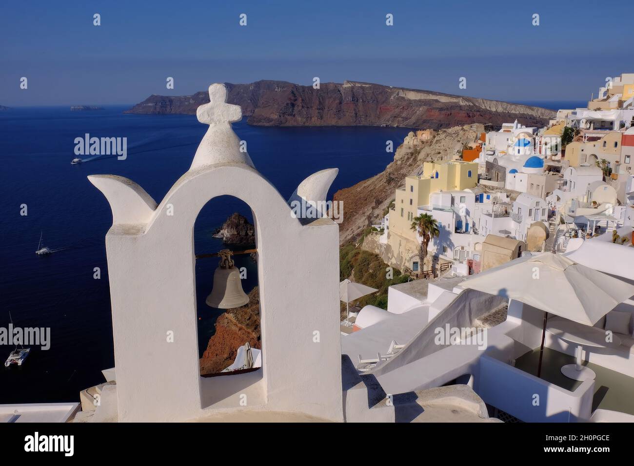 Sea, caldera, white bell tower and town soon after sunrise in Oia, Santorini Island (Thira), Cyclades, Greece Stock Photo