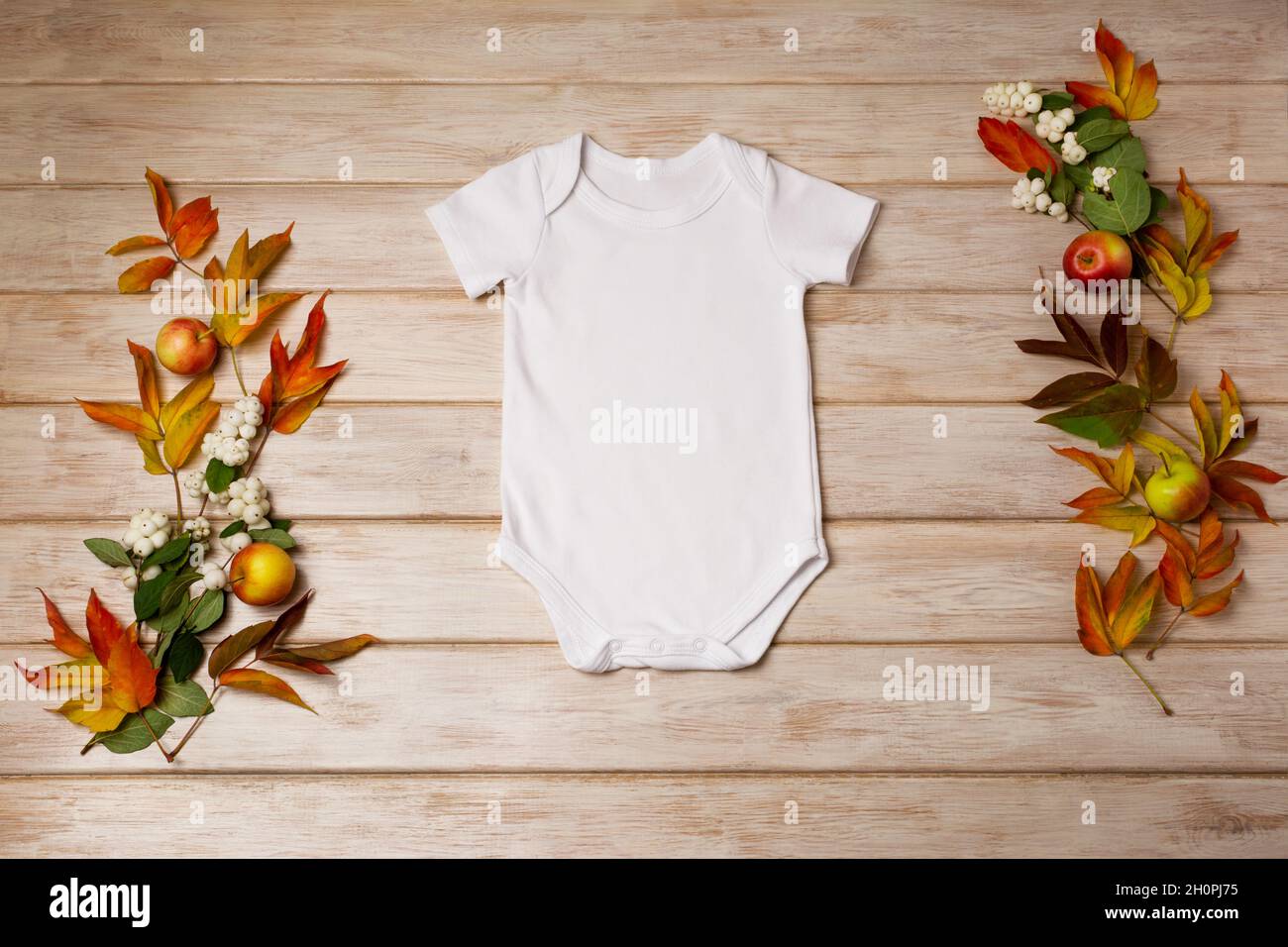 White cotton baby short sleeve onesie mockup with snowberry, red and green fall leaves. Design gender neutral bodysuit template, newborn romper print Stock Photo