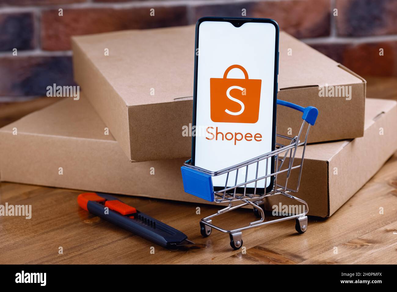 Shopee is e-commerce technology company. Smartphone with Shopee logo on the  screen, shopping cart and parcels Stock Photo - Alamy