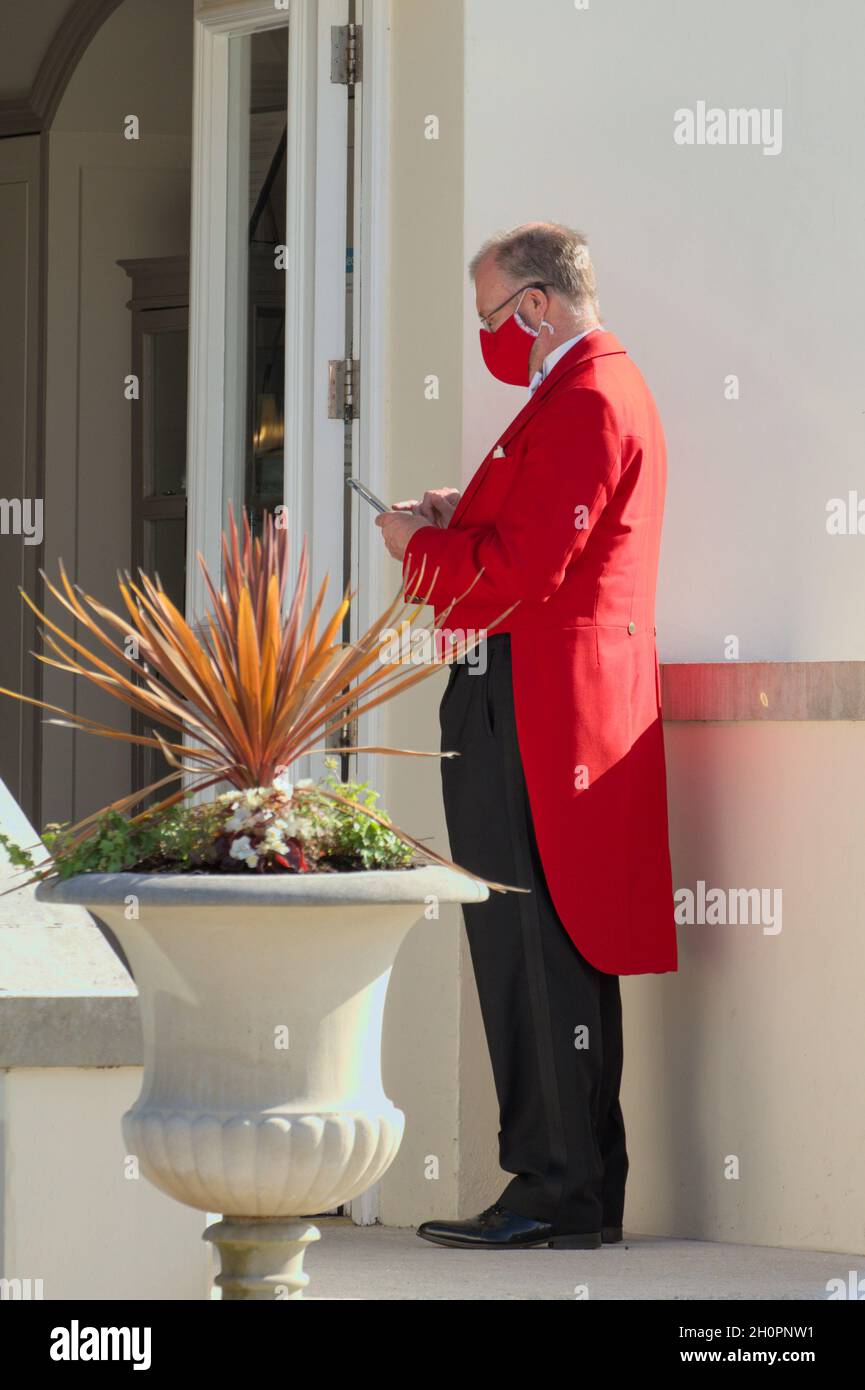 Wedding Toastmaster In Red Coat And Red Mask Reading A Phone, UK Stock Photo