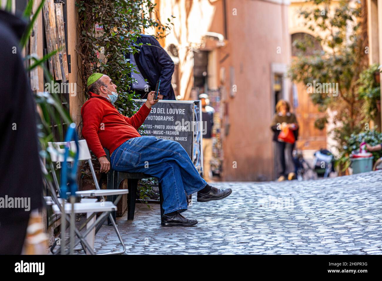 Man wearing yamaka looking at his phone in the Jewish Ghetto in Rome