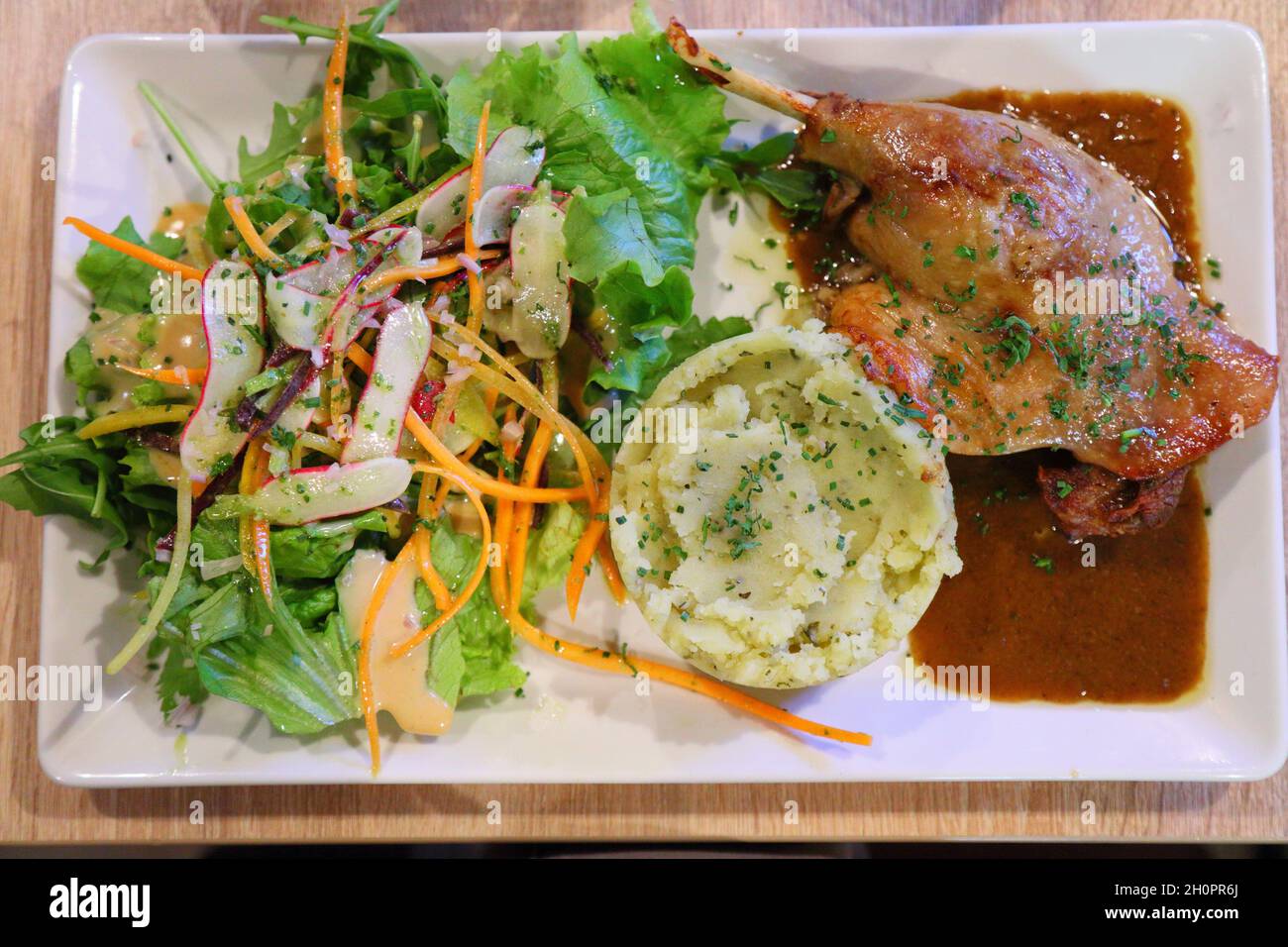 Duck leg confit with potato puree and fresh salad. French food. Cuisine of France. Stock Photo