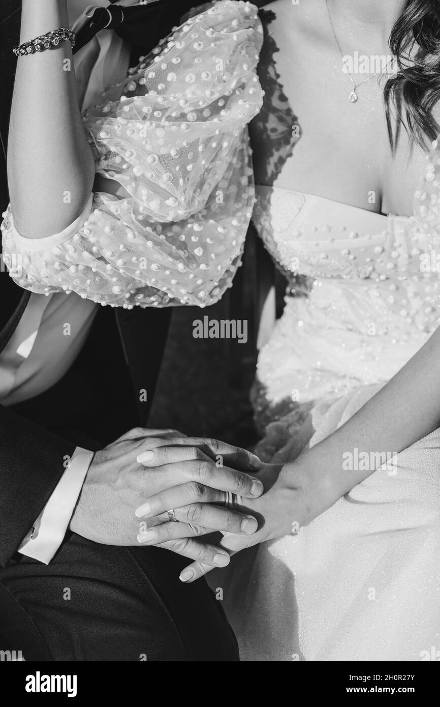 Black and white crop photo of bride and groom's hands in wedding dress. Unrecognizable persons. Stock Photo