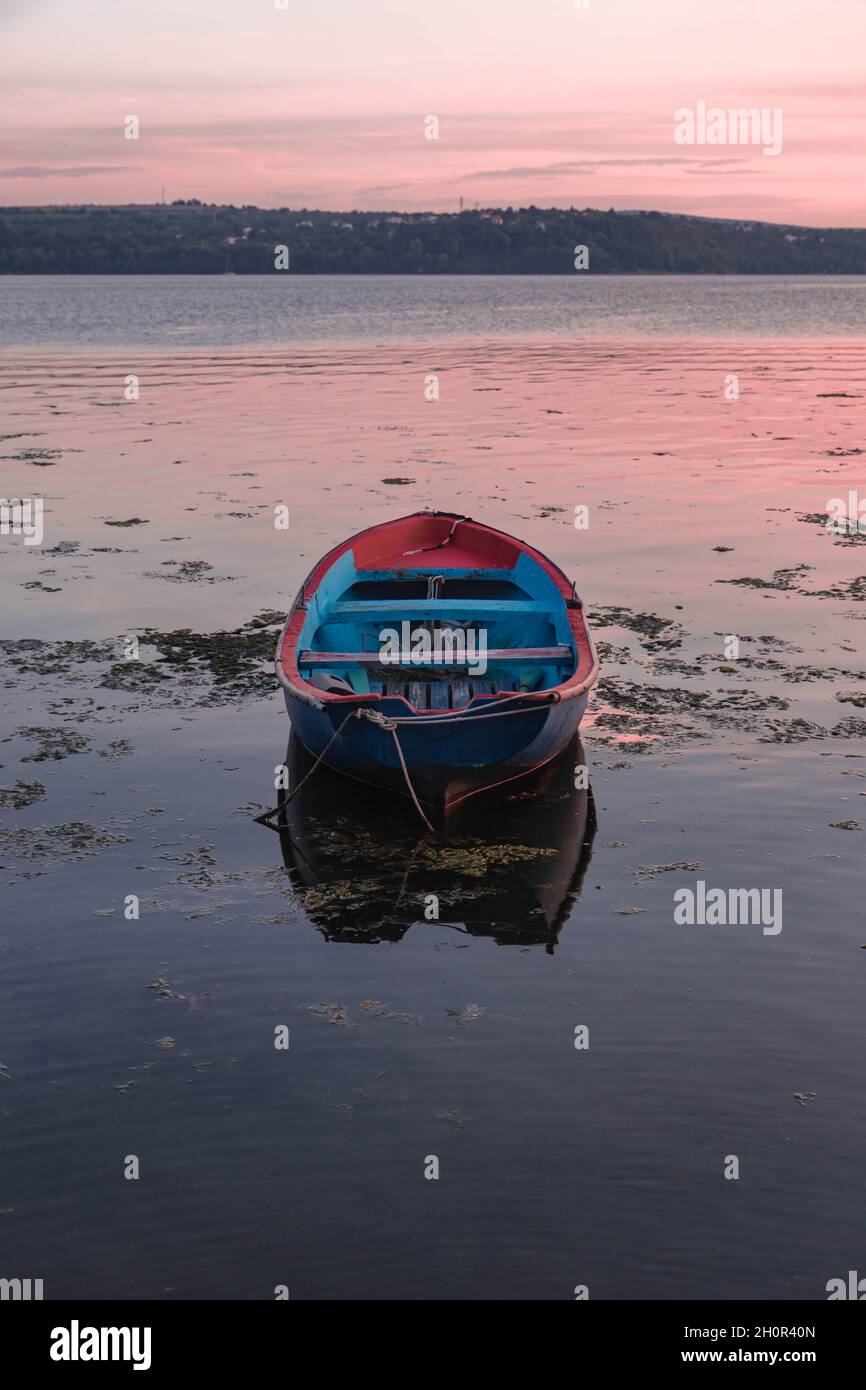 Vertical shot of a boat on a calm sea against a sunset sky Stock Photo ...