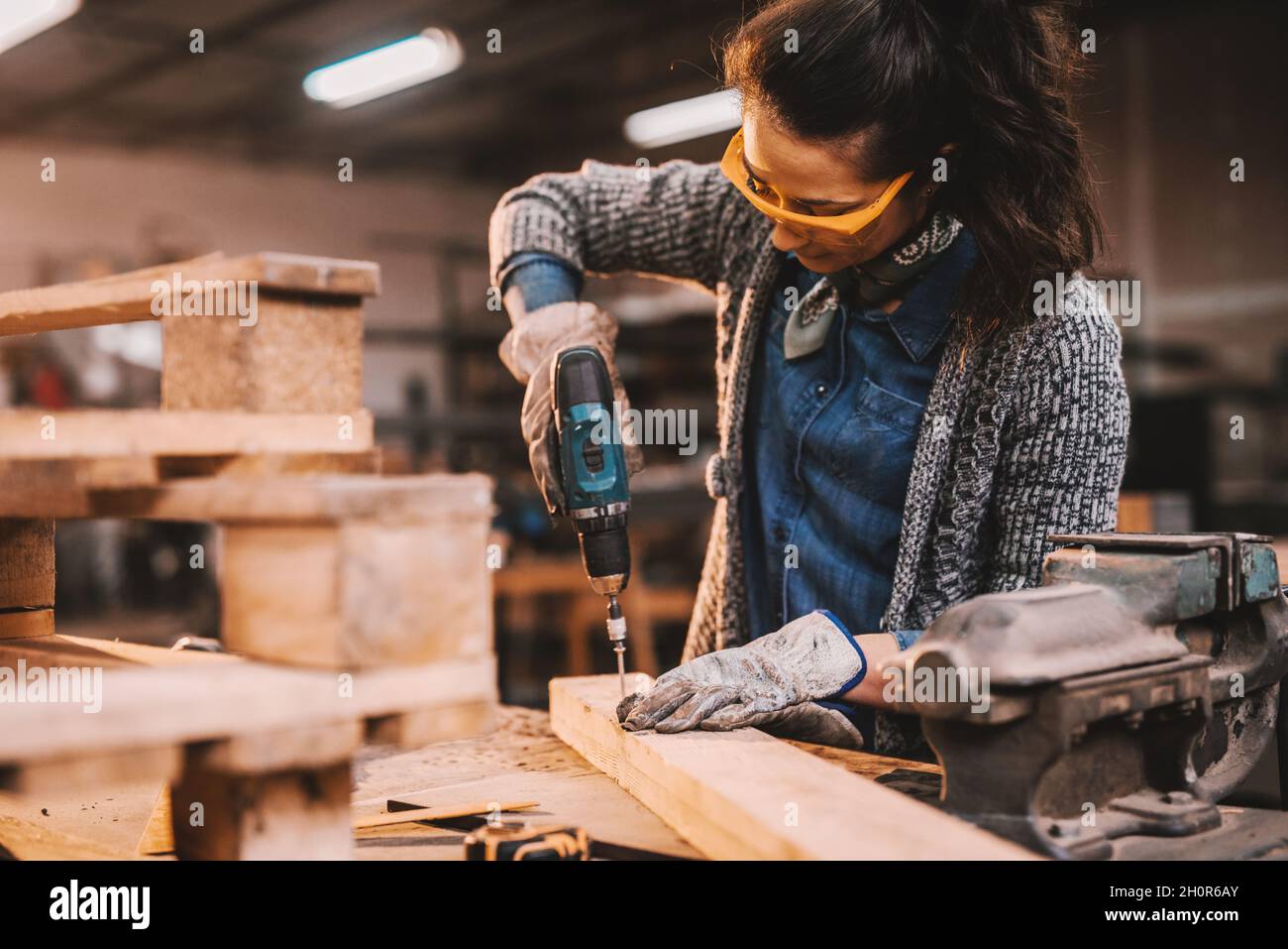 Female carpenter using drill while working in workshop. Female doing male's work concept. Stock Photo