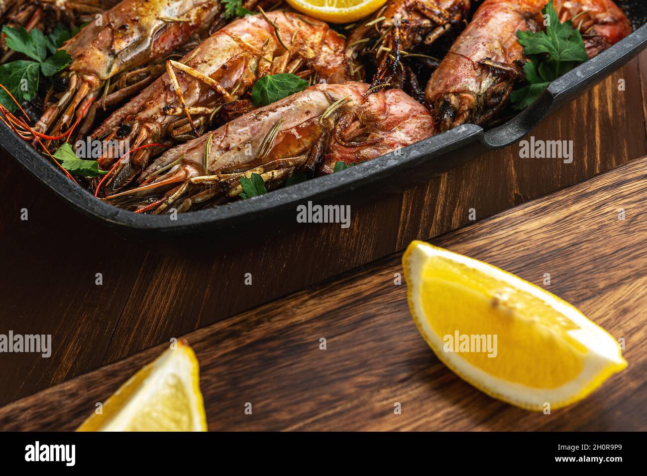 Fried shrimps on grill pan with fresh herbs and lemon slice. Seafood