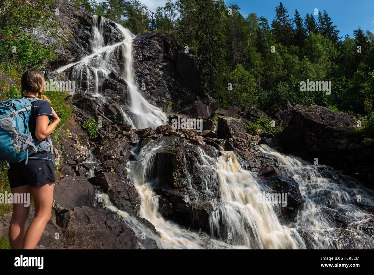 Tourist admires Elgafossen - Algafallet Waterfall shared between Sweden and Norway Stock Photo