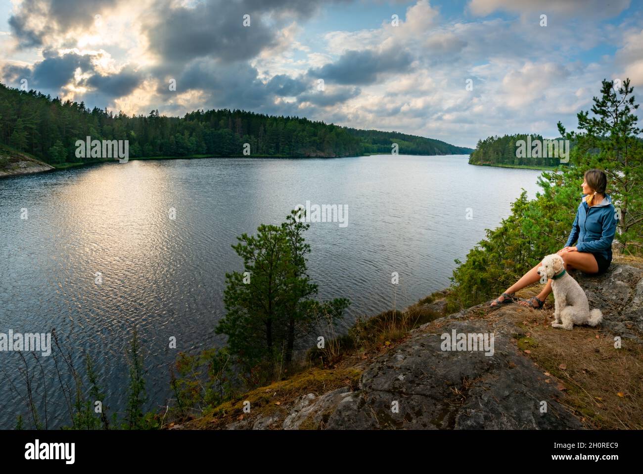 Young Woman with her dog admires beautiful Vansjo Lake Norway Stock Photo
