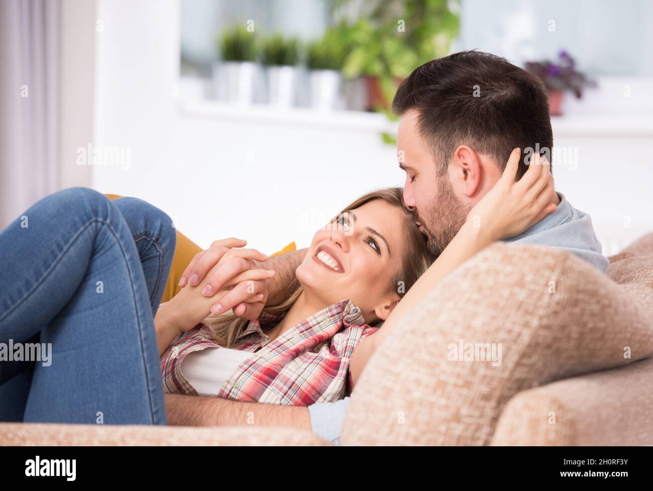 Young couple in love, having intimate moments, hugging and kissing on sofa  at home Stock Photo - Alamy