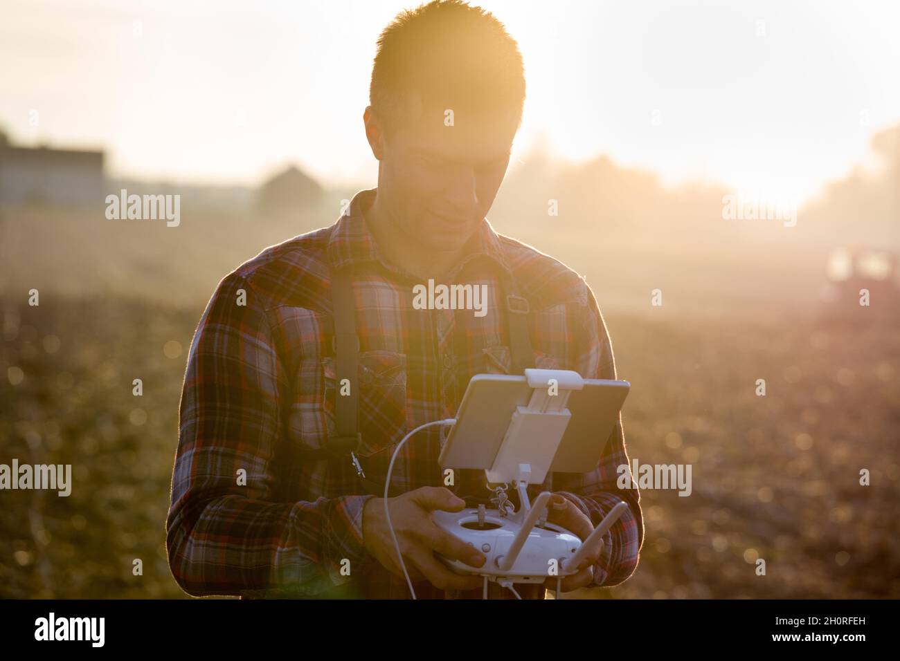 Farmer holding remote control with tablet for drone in field. High