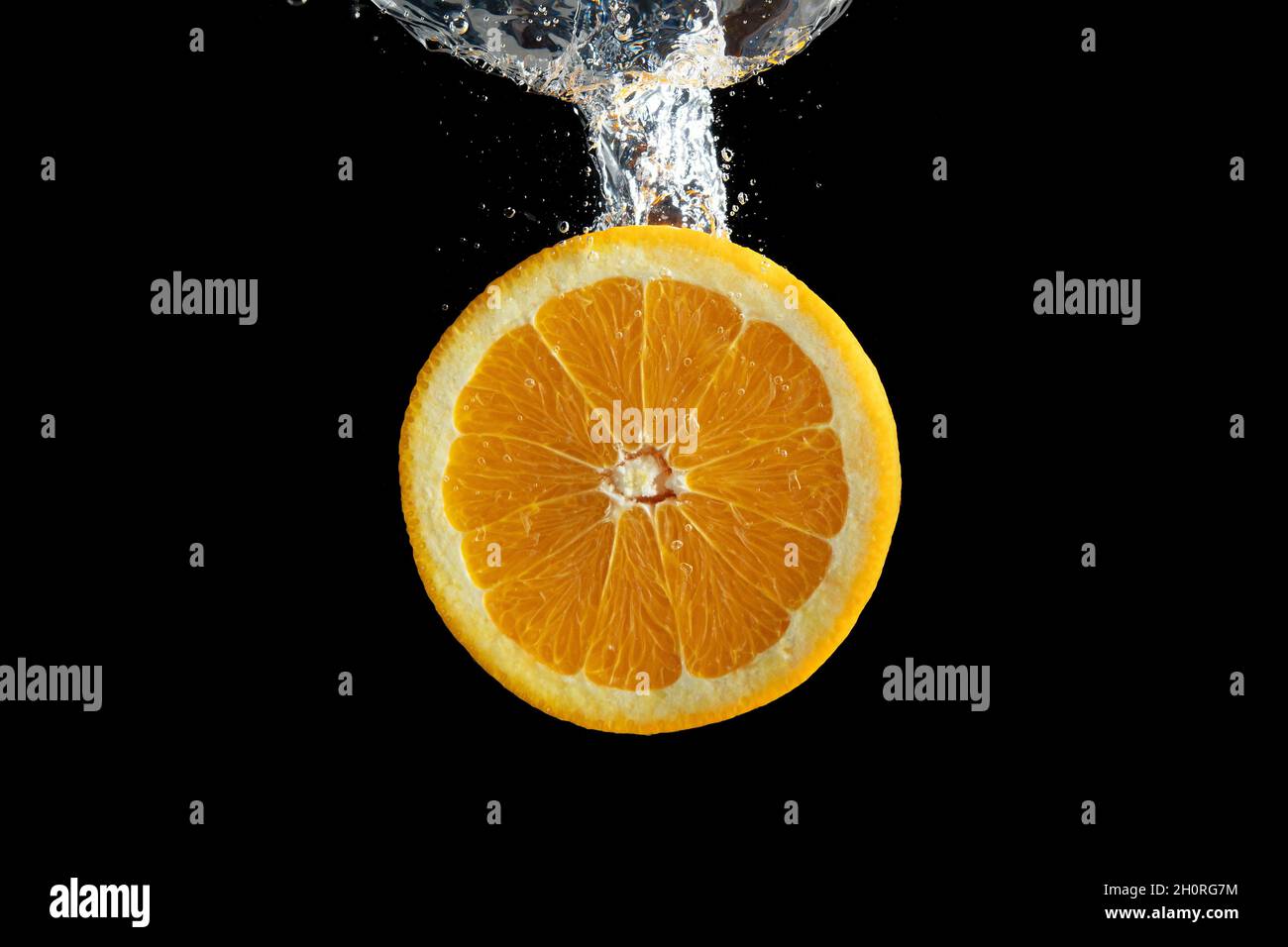 Fresh sliced orange fruit in water splash isolated on black background ...