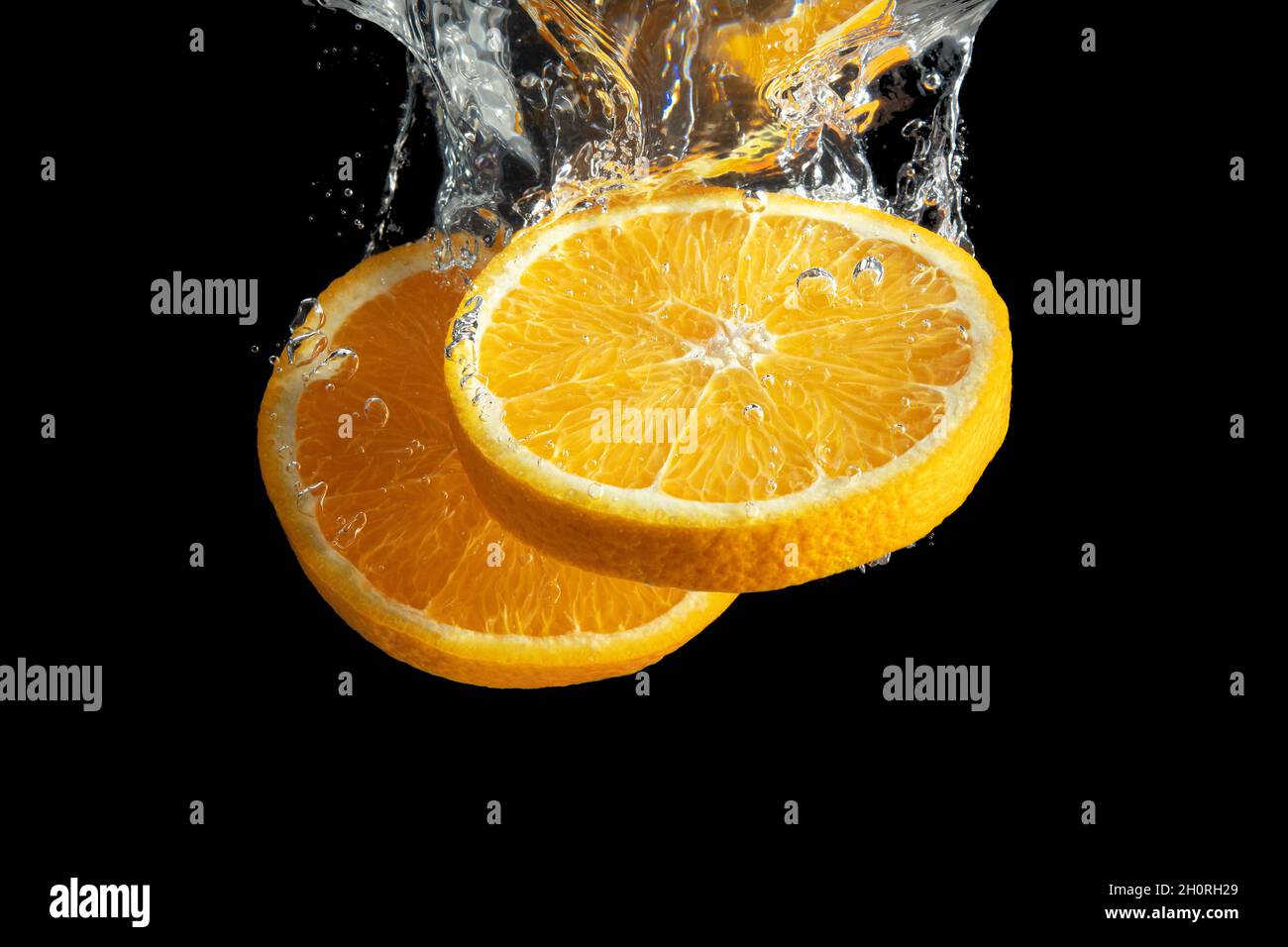Fresh sliced orange fruit in water splash isolated on black background ...