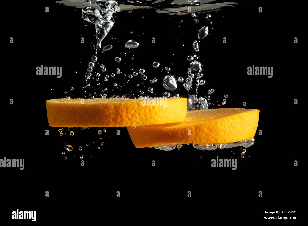 Fresh sliced orange fruit in water splash isolated on black background ...