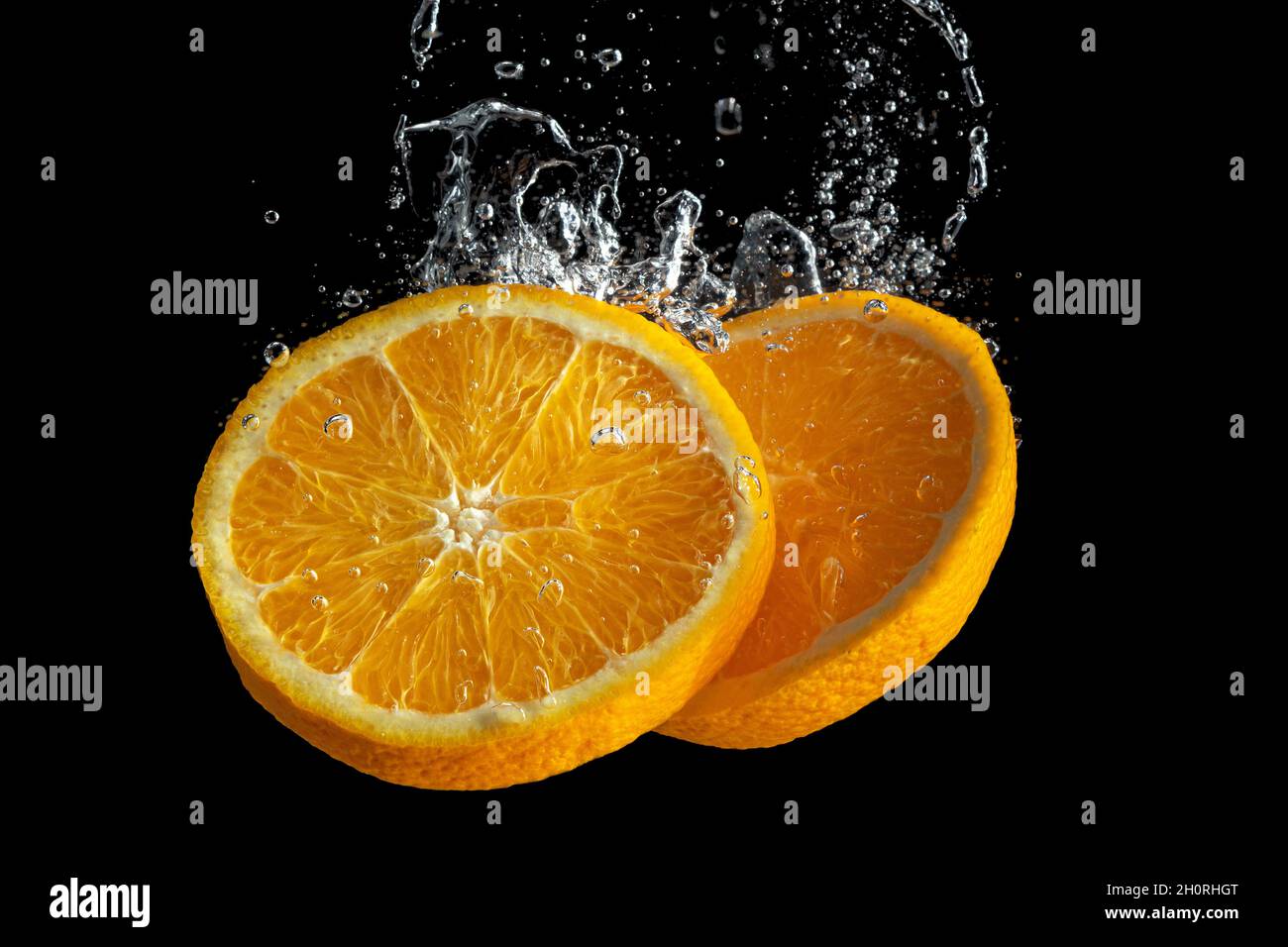 Fresh sliced orange fruit in water splash isolated on black background ...
