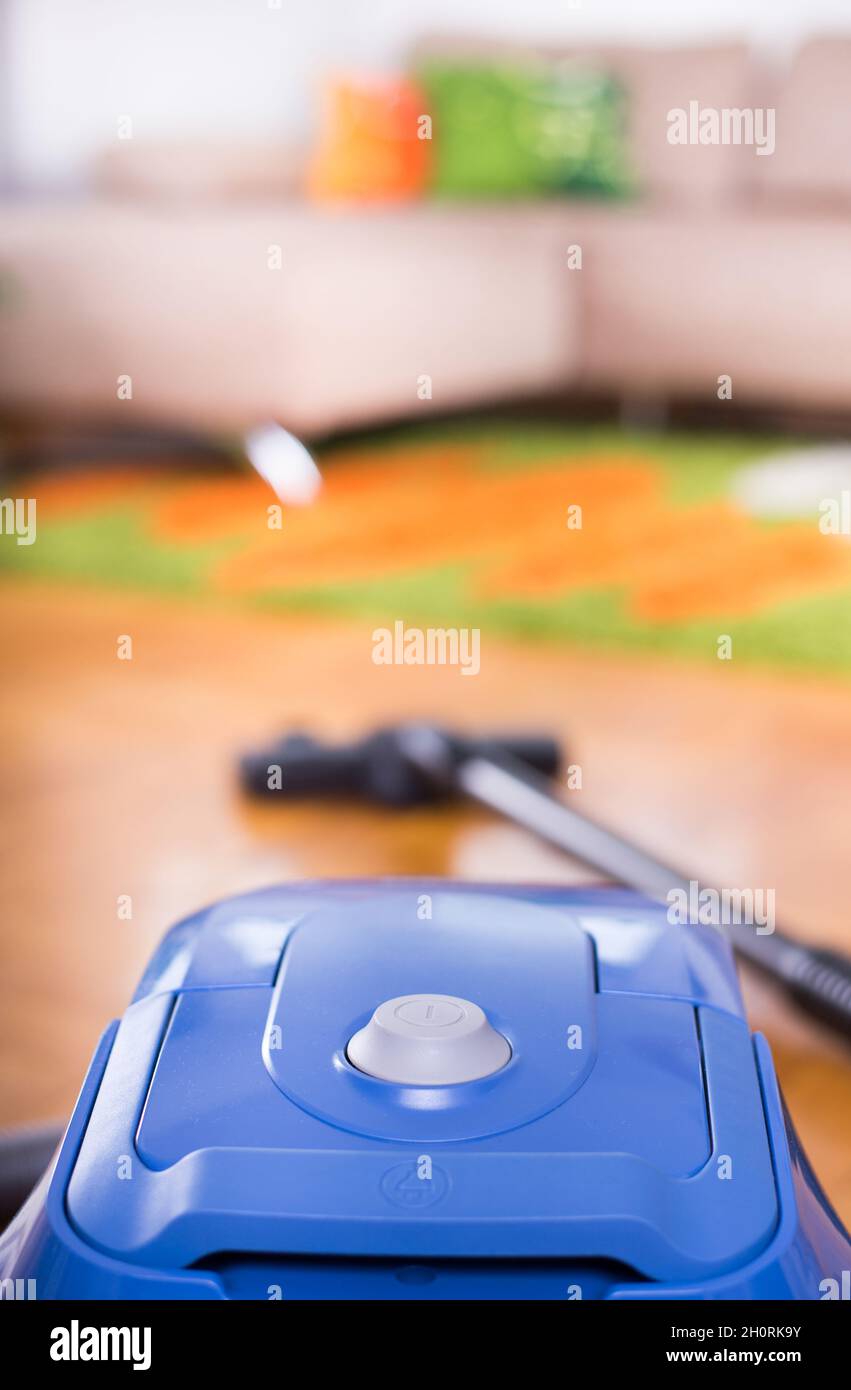 Close up of turn on button of vacuum cleaner on floor of living room