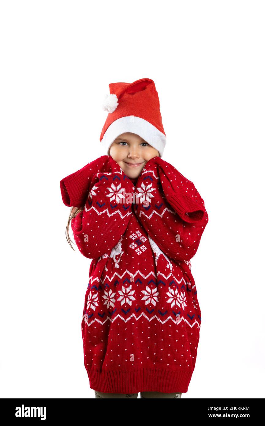 portrait of cute girl in red knitted oversized Christmas sweater with reindeer with long sleeves, isolated on white background, concept of growing up Stock Photo