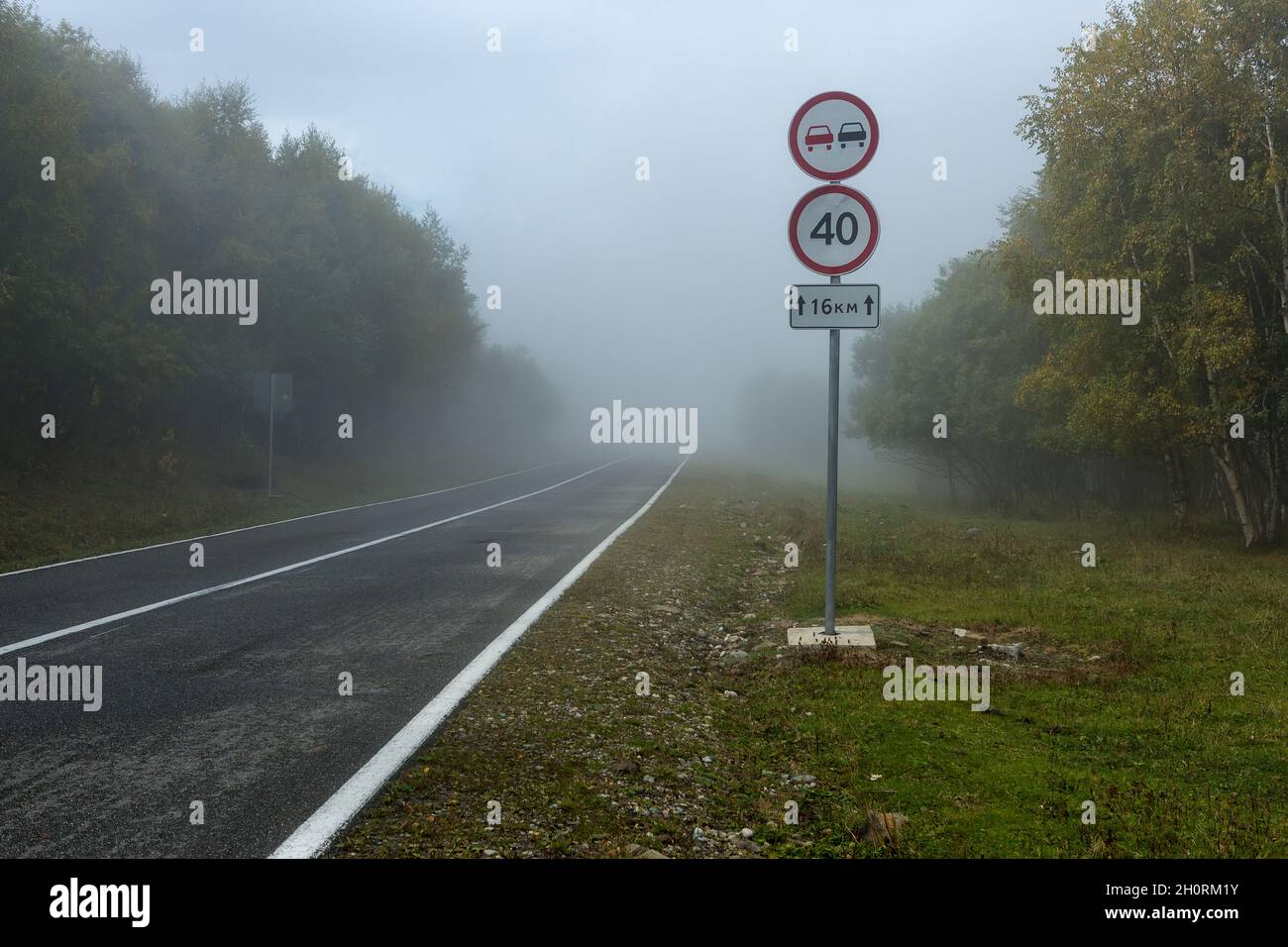 Dangerous fog on the road in the mountains, speed limit road sign Stock ...