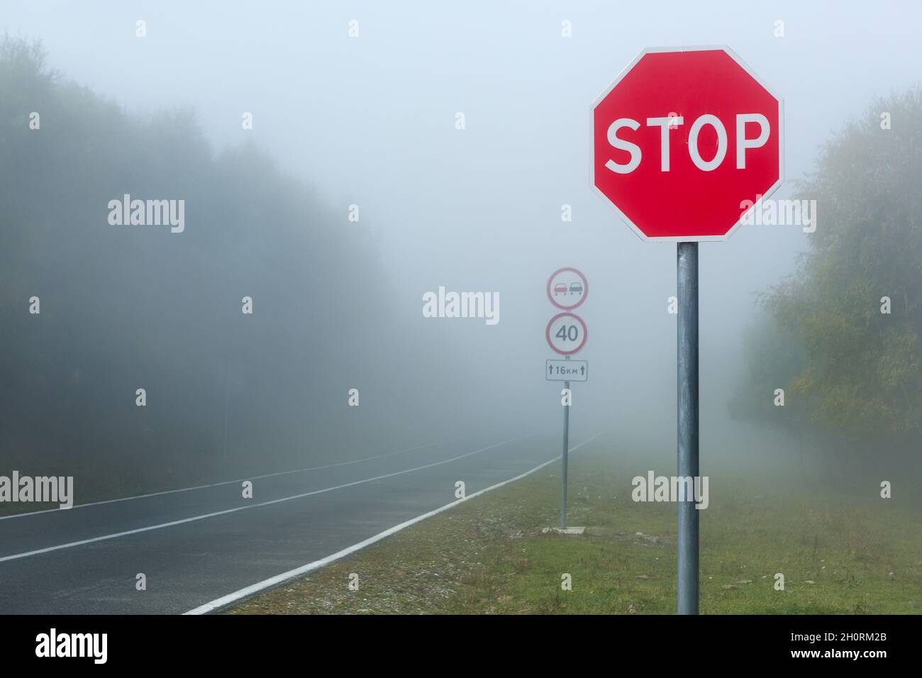 Dangerous fog on the road in the mountains, speed limit road sign Stock Photo
