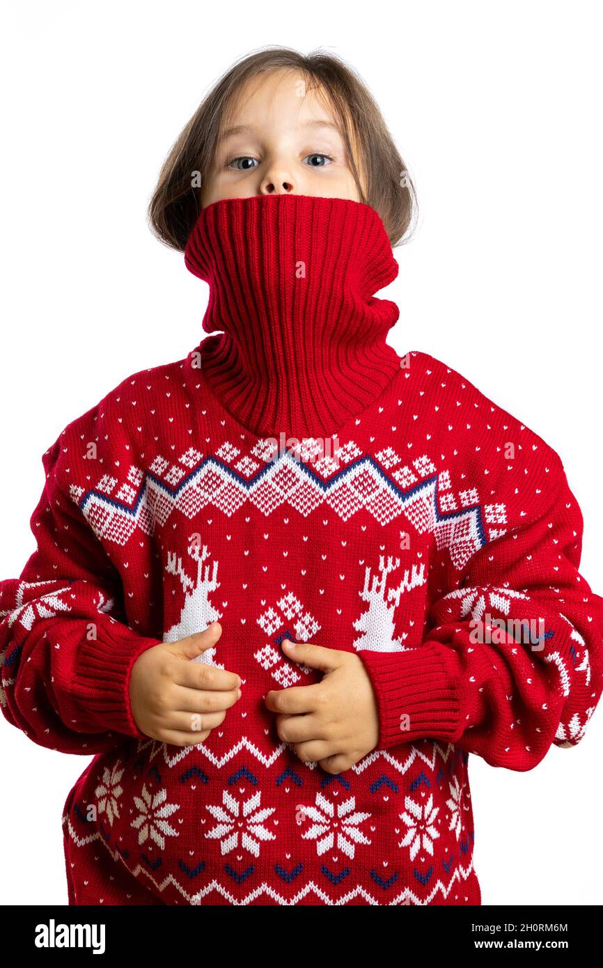 mischievous face of little girl half peeks out of knitted collar of Christmas sweater with reindeer, isolated on white background Stock Photo