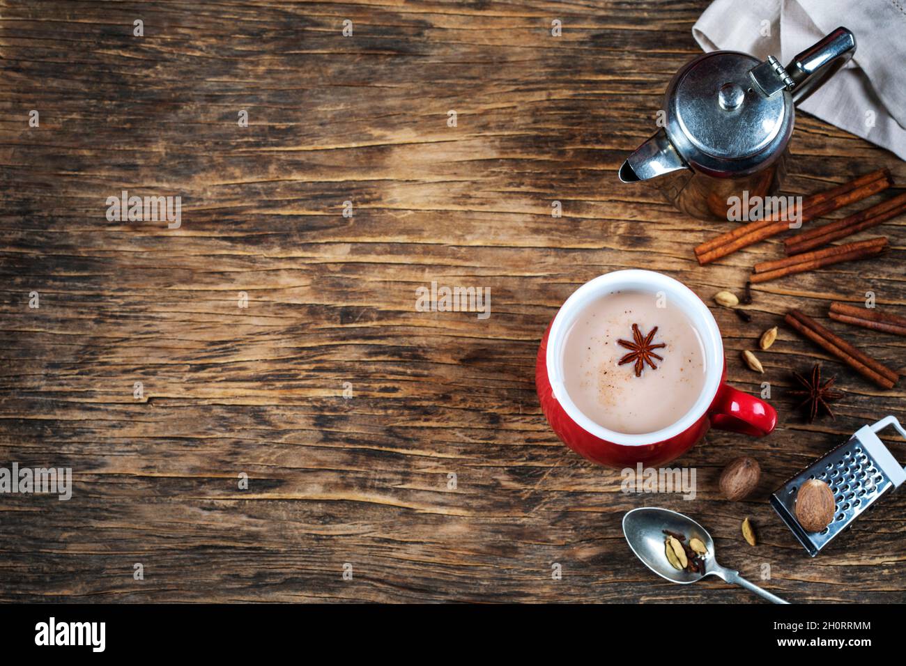 Cup of masala chai tea on a table with fresh spices and kitchen equipment Stock Photo