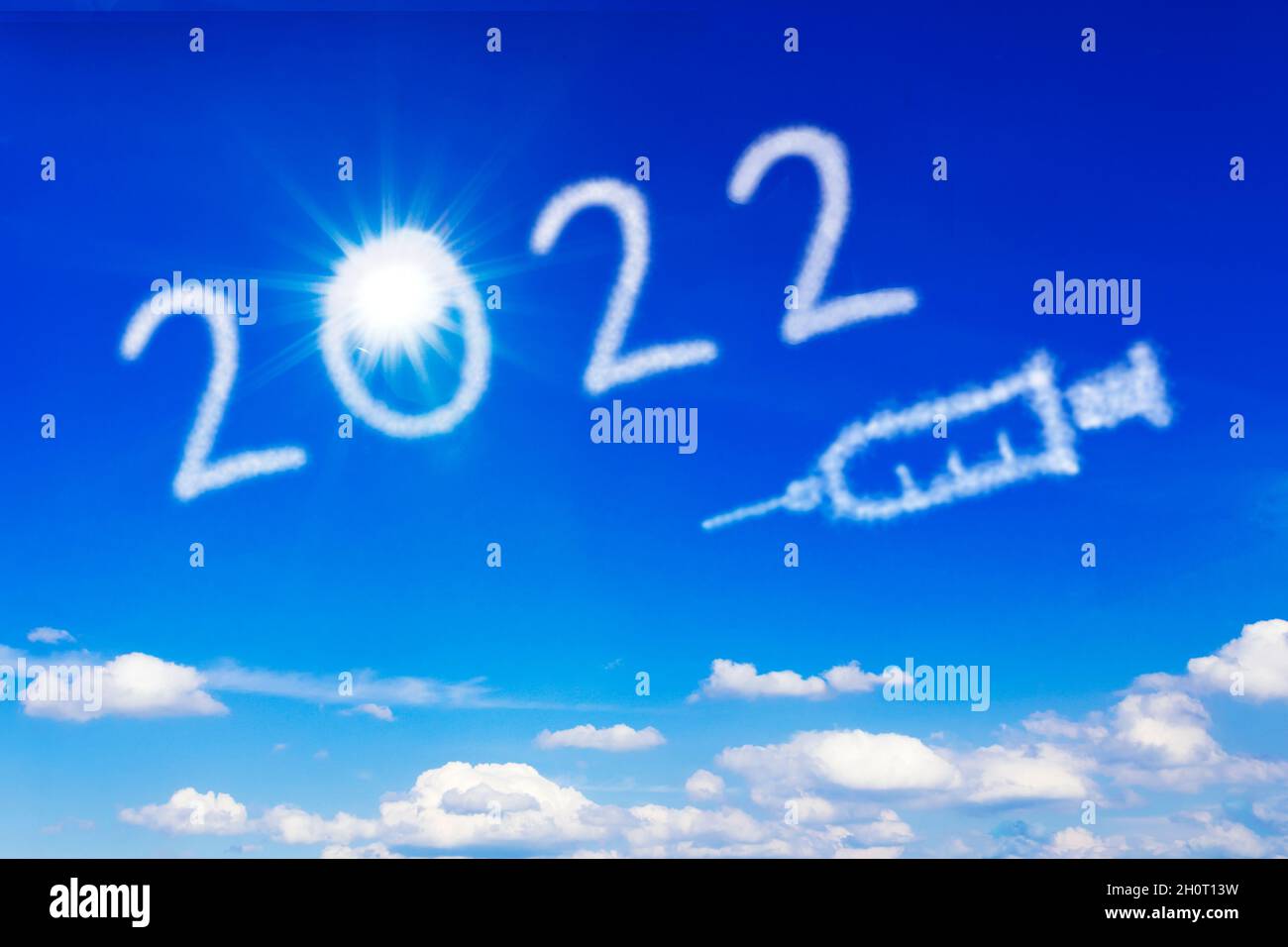 Happy New Year concept. Bright sun, number 2022 and a syringe icon on blue sky, symbolising an end to the covid pandemic. Stock Photo