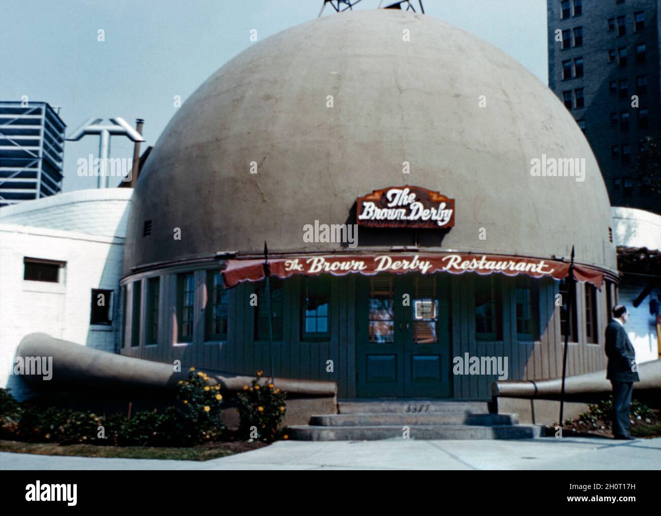 The original Brown Derby restaurant at 3427 Wilshire Boulevard, Los Angeles, California, USA in the 1950s. The first and best known of an eventual restaurant chain was shaped like a man's derby hat, an iconic image that became synonymous with the Golden Age of Hollywood. It was opened by Wilson Mizner in 1926. The restaurants closed in the 1980s but a Disney-backed Brown Derby national franchising programme revived the brand in the 21st century – a vintage 1950s photograph. Stock Photo