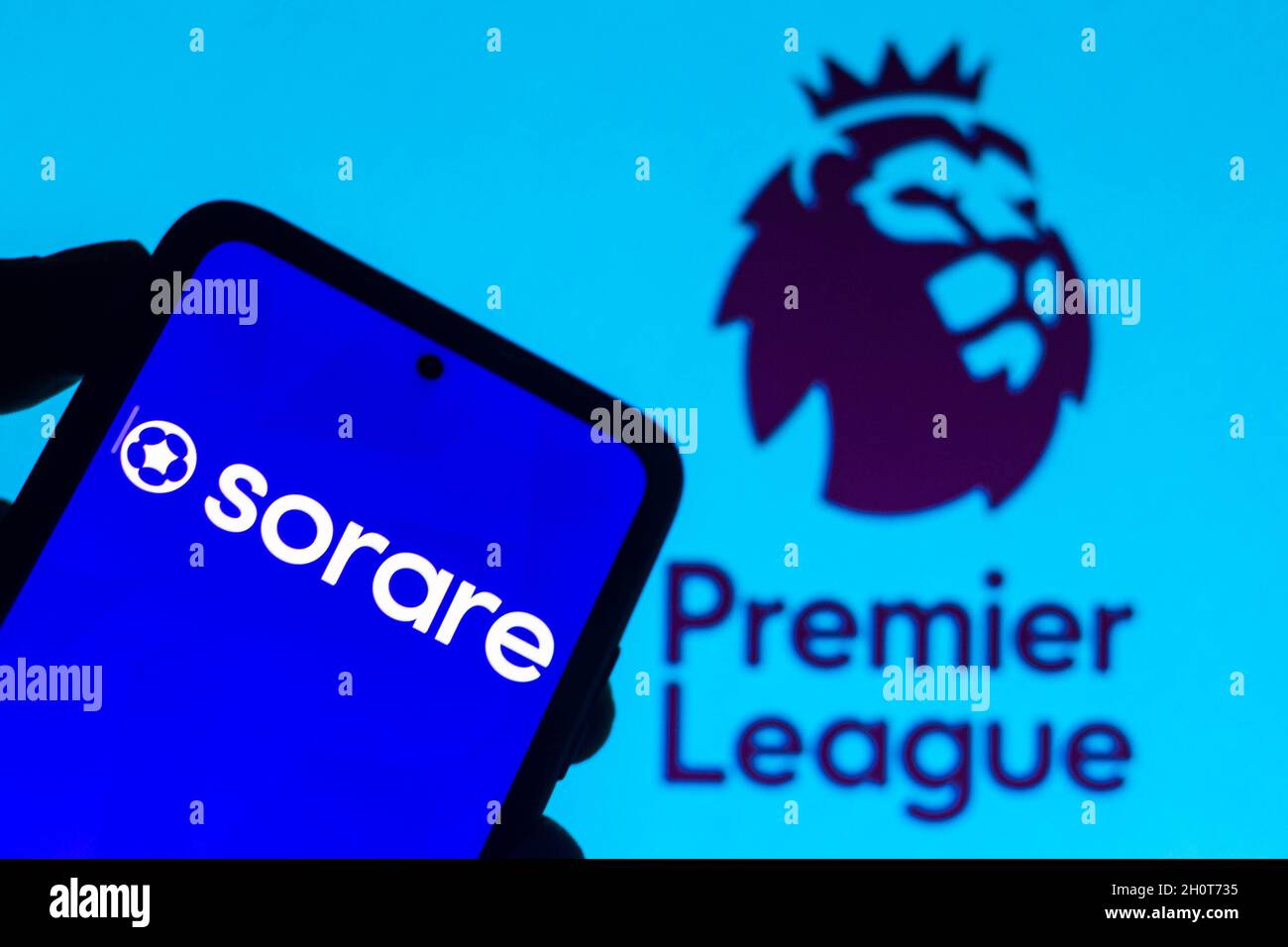 In this photo illustration, Sorare logo seen displayed on a smartphone and the Premier League in the background. Stock Photo