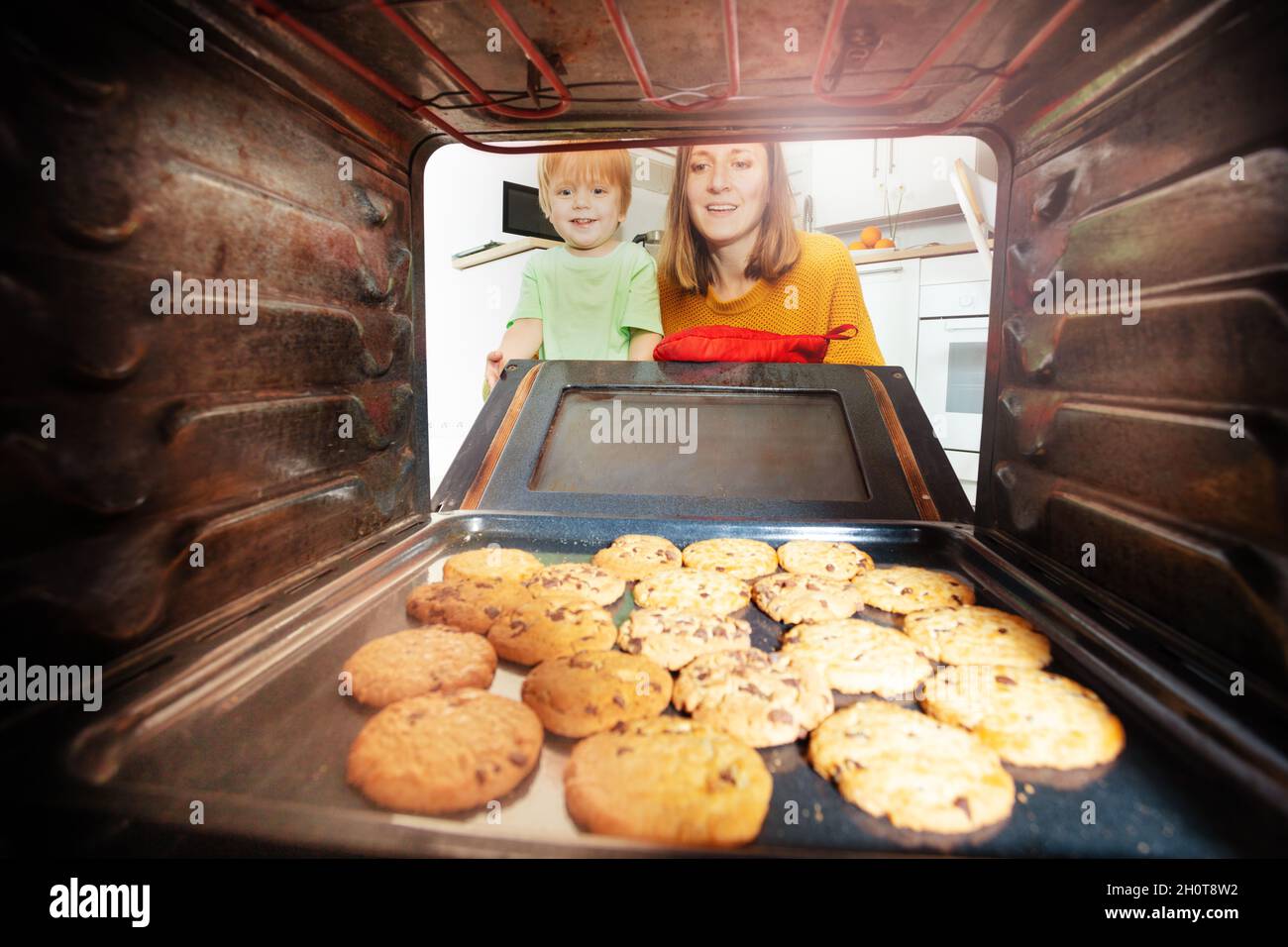 Mother and child open oven door, look at biscuits Stock Photo