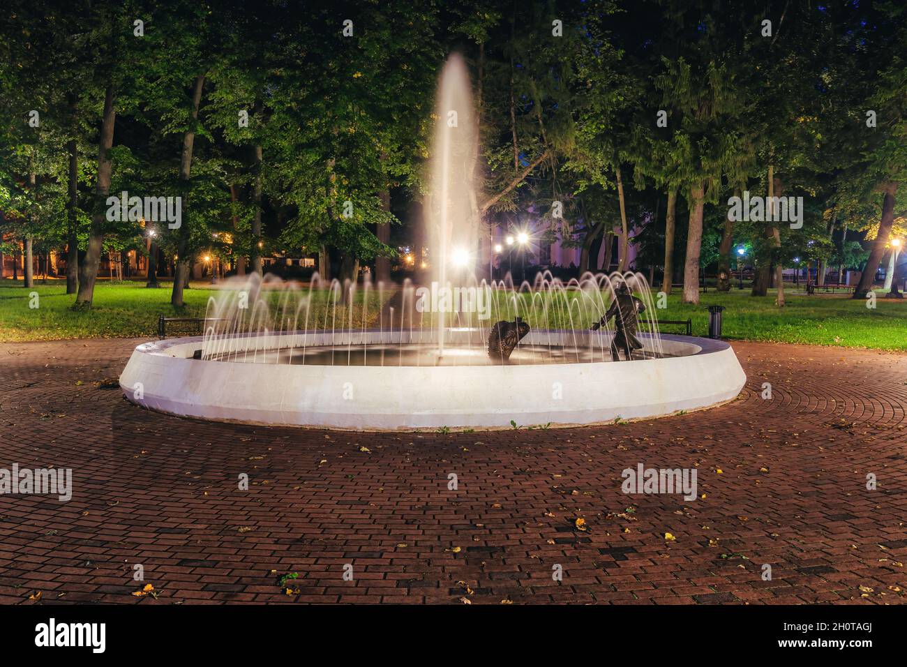 A fountain with blurred streams of water in a night park illuminated by ...