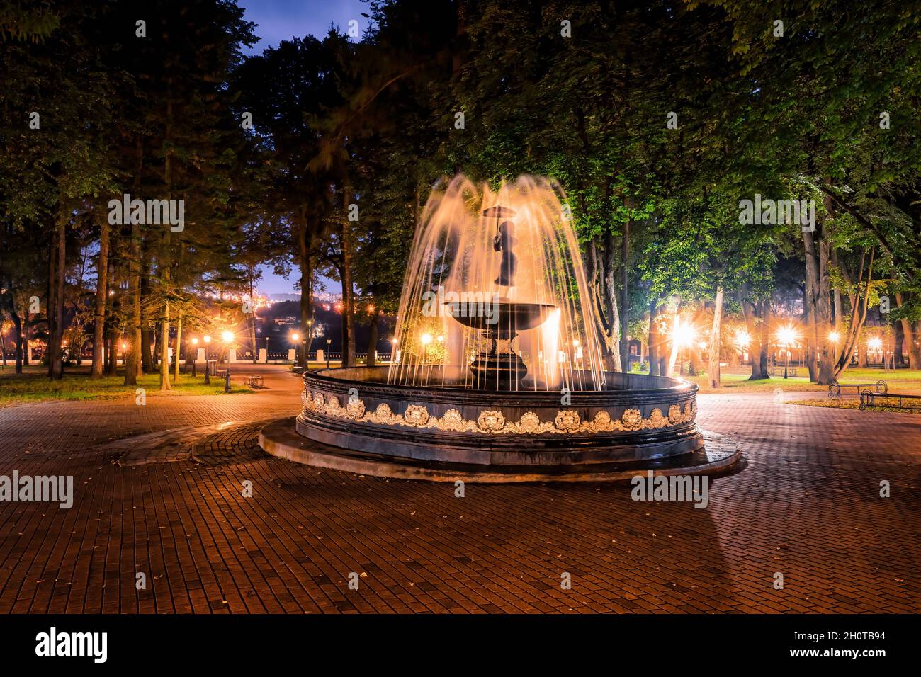 A fountain with blurred streams of water in a night park illuminated by ...