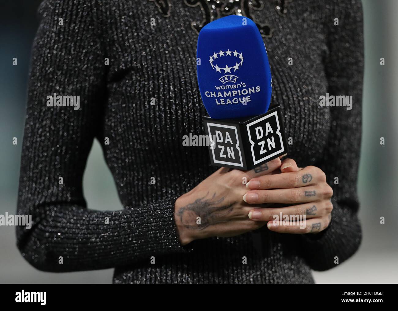 Turin, Italy, 13th October 2021. The tattooed hands of DAZN TV presenter  Ema Stokholma as she holds a DAZN and UEFA Women's Champions League branded  microphone during the UEFA Womens Champions League