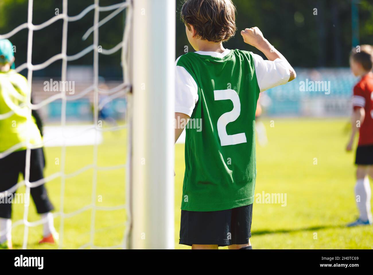 Happy boy standing in football goal during corner kick. School kids playing football game on grass pitch Stock Photo