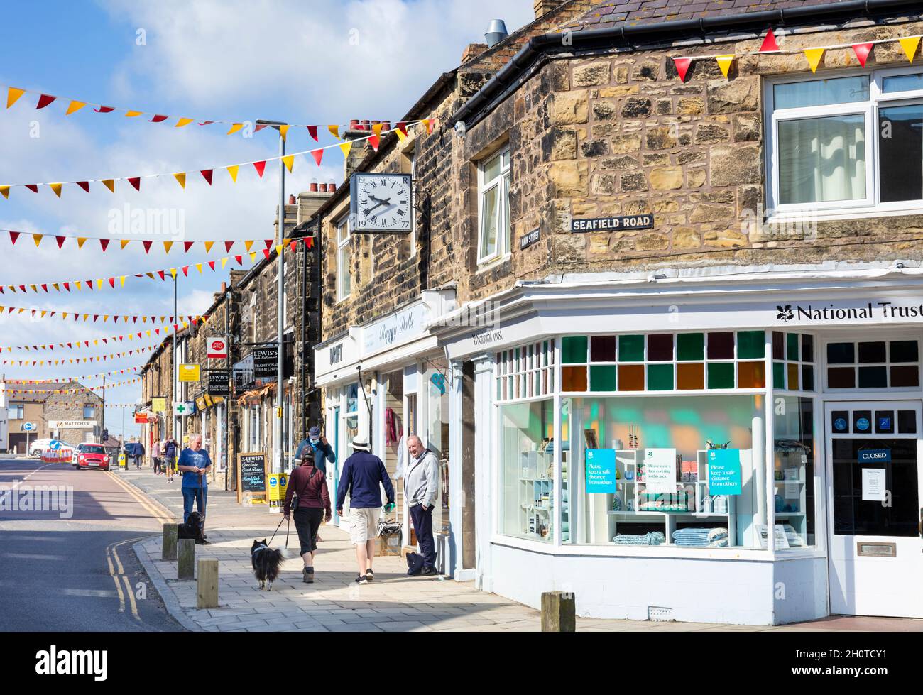 Shops on the Main street decked in bunting through Seahouses and the National Trust shop Seahouses Northumberland England UK GB Europe Stock Photo