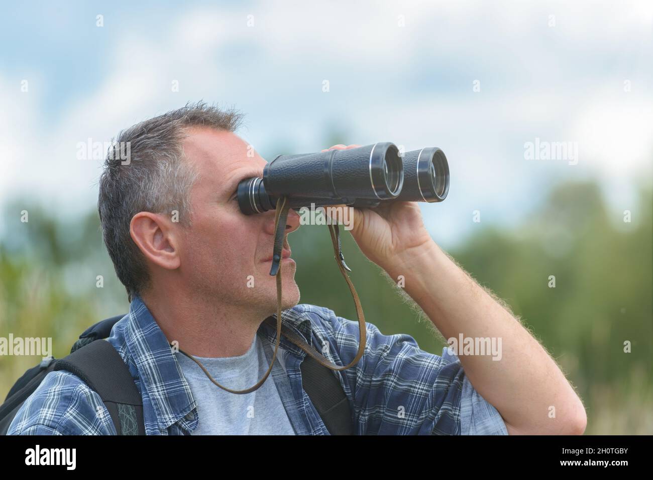 Close up of a man looking through binoculars, outdoors. Stock Photo