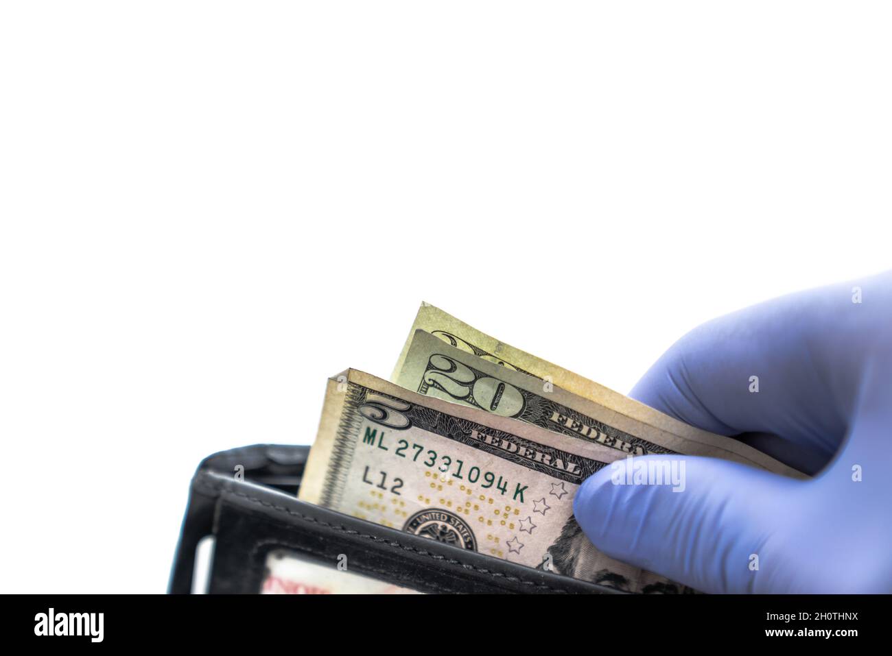 Close up of person pulling cash including a five and two twenty dollar bills out of a black leather wallet wearing a blue latex glove isolated on a wh Stock Photo