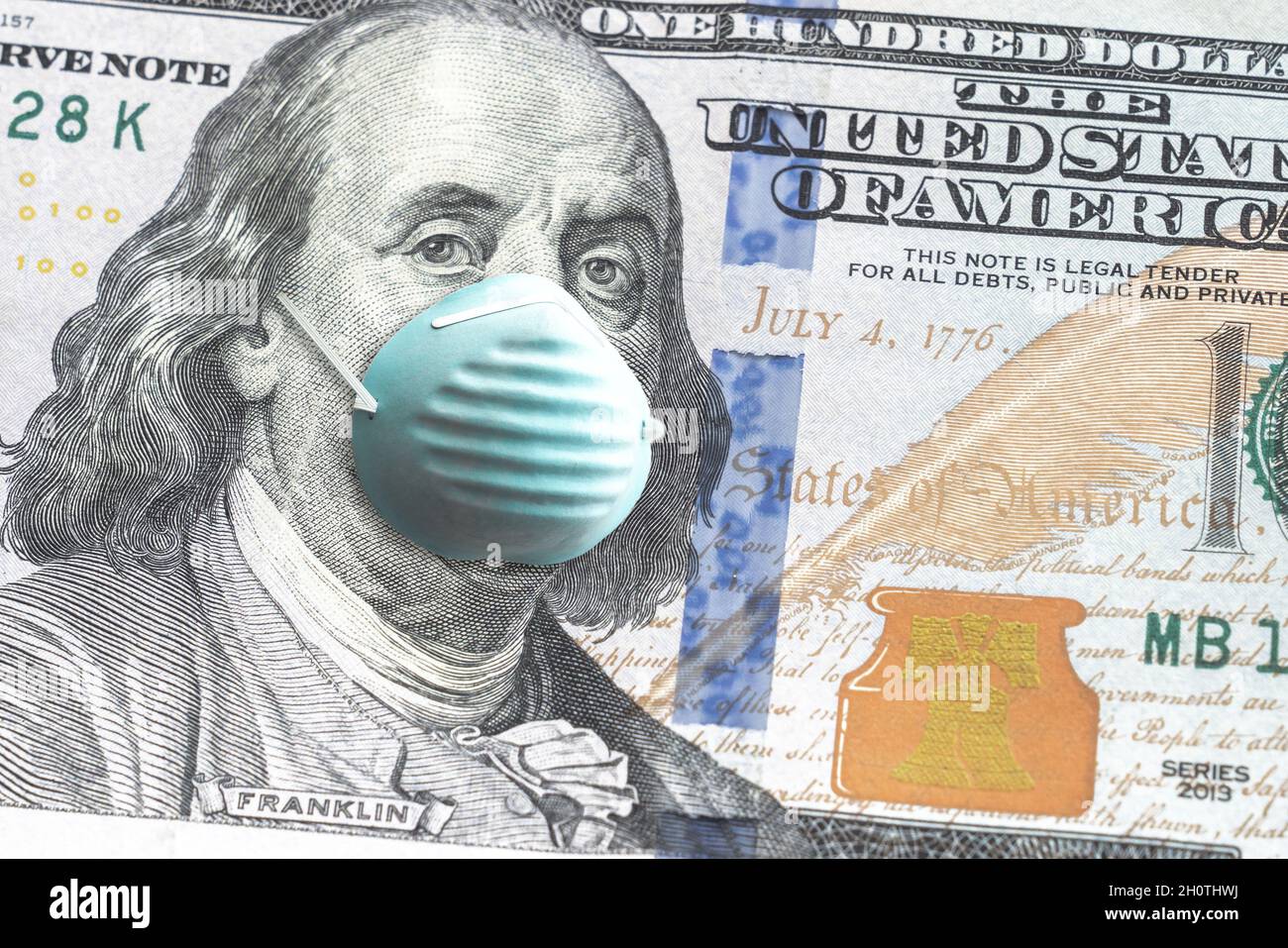 Close up of United States paper currency one hundred dollar bill with Benjamin Franklin wearing blue face mask due to COVID-19 pandemic making a great Stock Photo