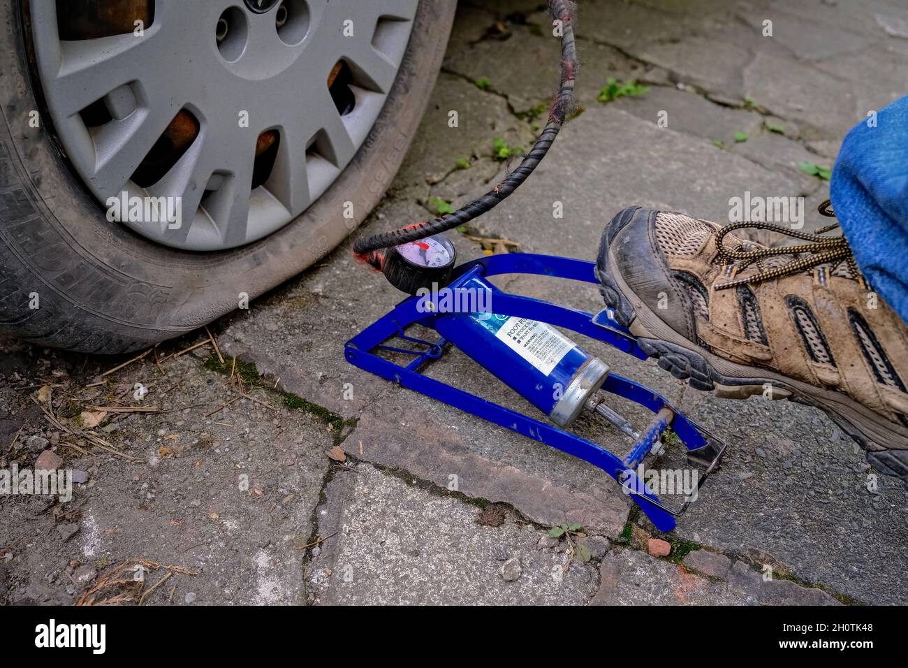 man operating a manual air pressure foot pump to inflate flat punctured car tyre Stock Photo