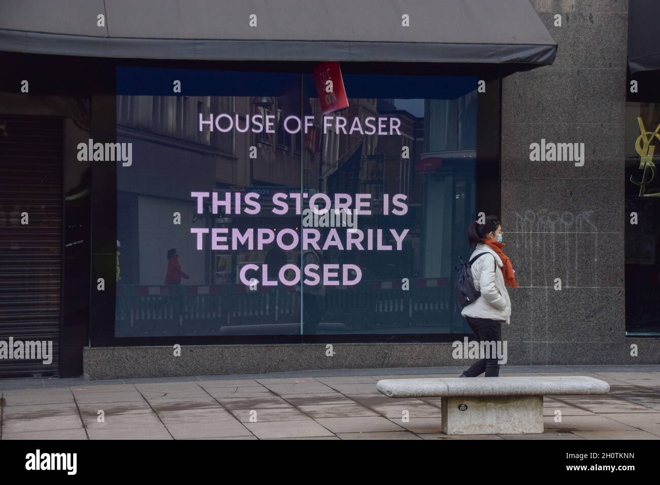 A woman with a face mask walks past a Closed store sign at House of Fraser department store on Oxford Street during the nationwide coronavirus lockdown in England. 10th February 2021. Stock Photo