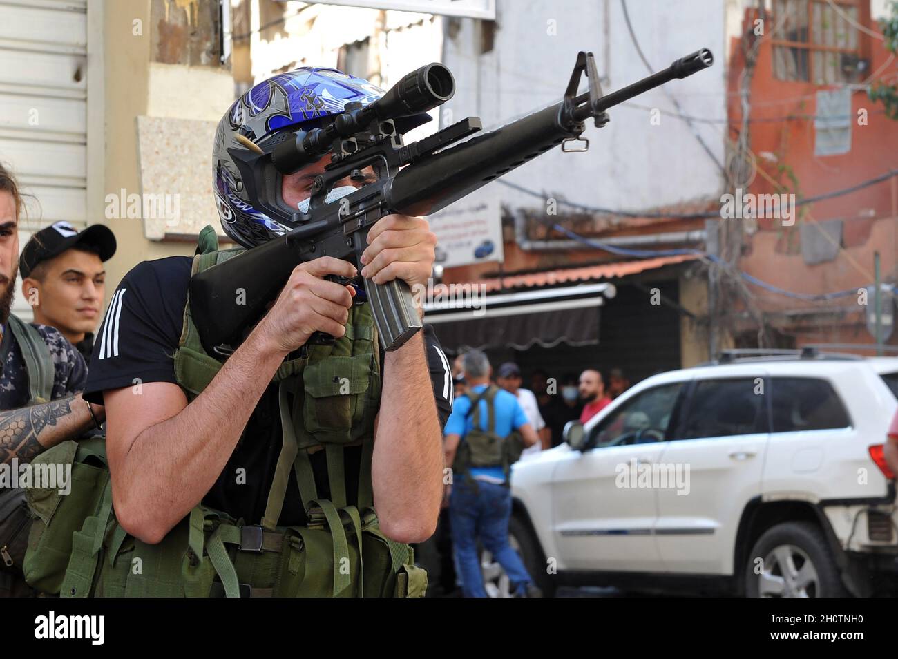 Beirut, Lebanon. 14th Oct, 2021. Shiite fighter from Hezbollah and Amal movements takes aim with a Kalashnikov assault rifle amidst clashes in the area of Tayouneh, in the southern suburb of the capital Beirut, on Thursday on October 14, 2021. Armed clashes broke out in Beirut Thursday during the protest against the lead judge investigating last year's massive blast in the city's port, as tensions over the domestic probe boiled over. Photo by Jamal Eddine/ Credit: UPI/Alamy Live News Stock Photo