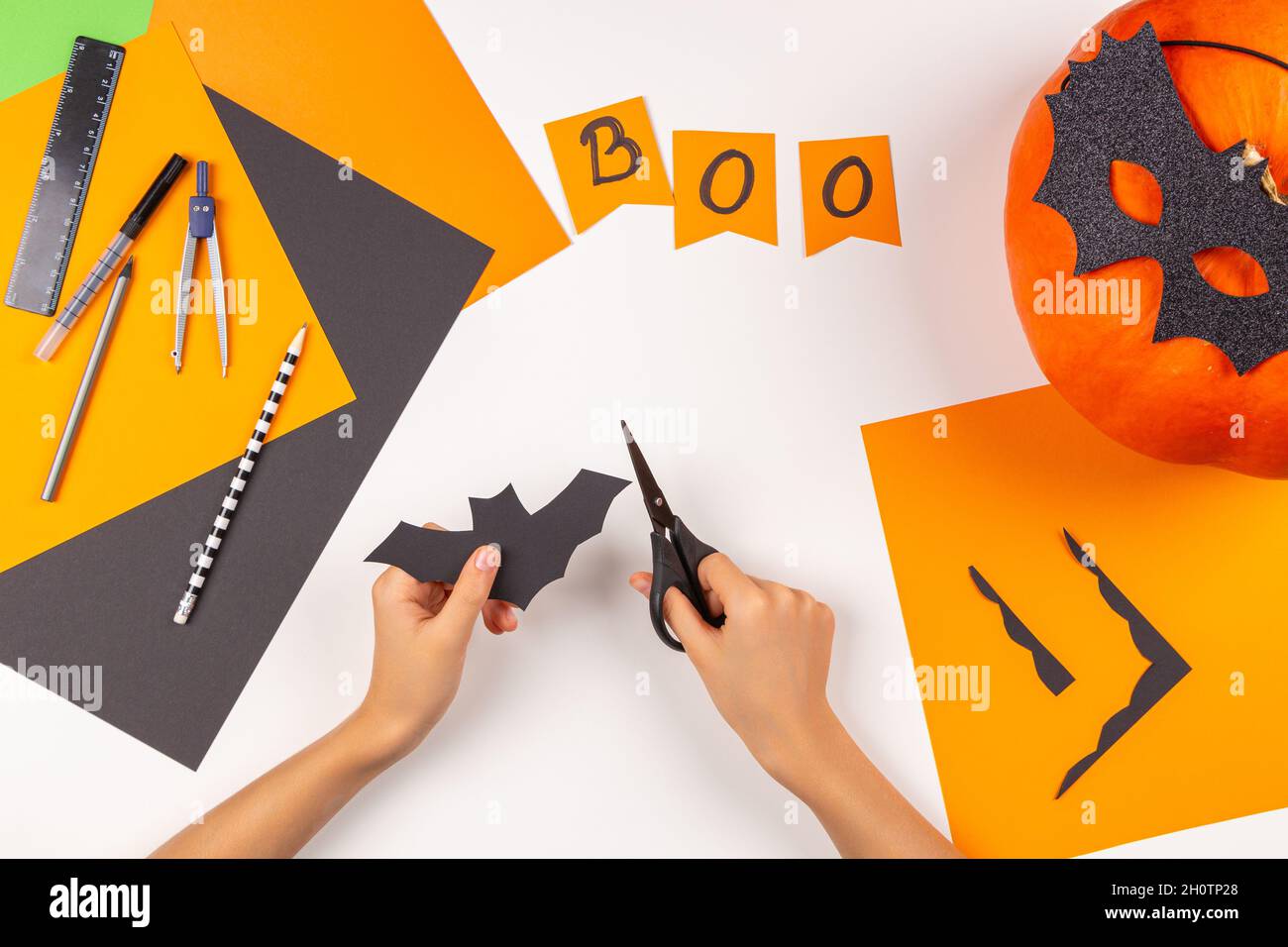 Preparing for Halloween. Teenage kid hands cutting black paper bat with  scissors and making Halloween party decorations on white table at home. Top  Stock Photo - Alamy